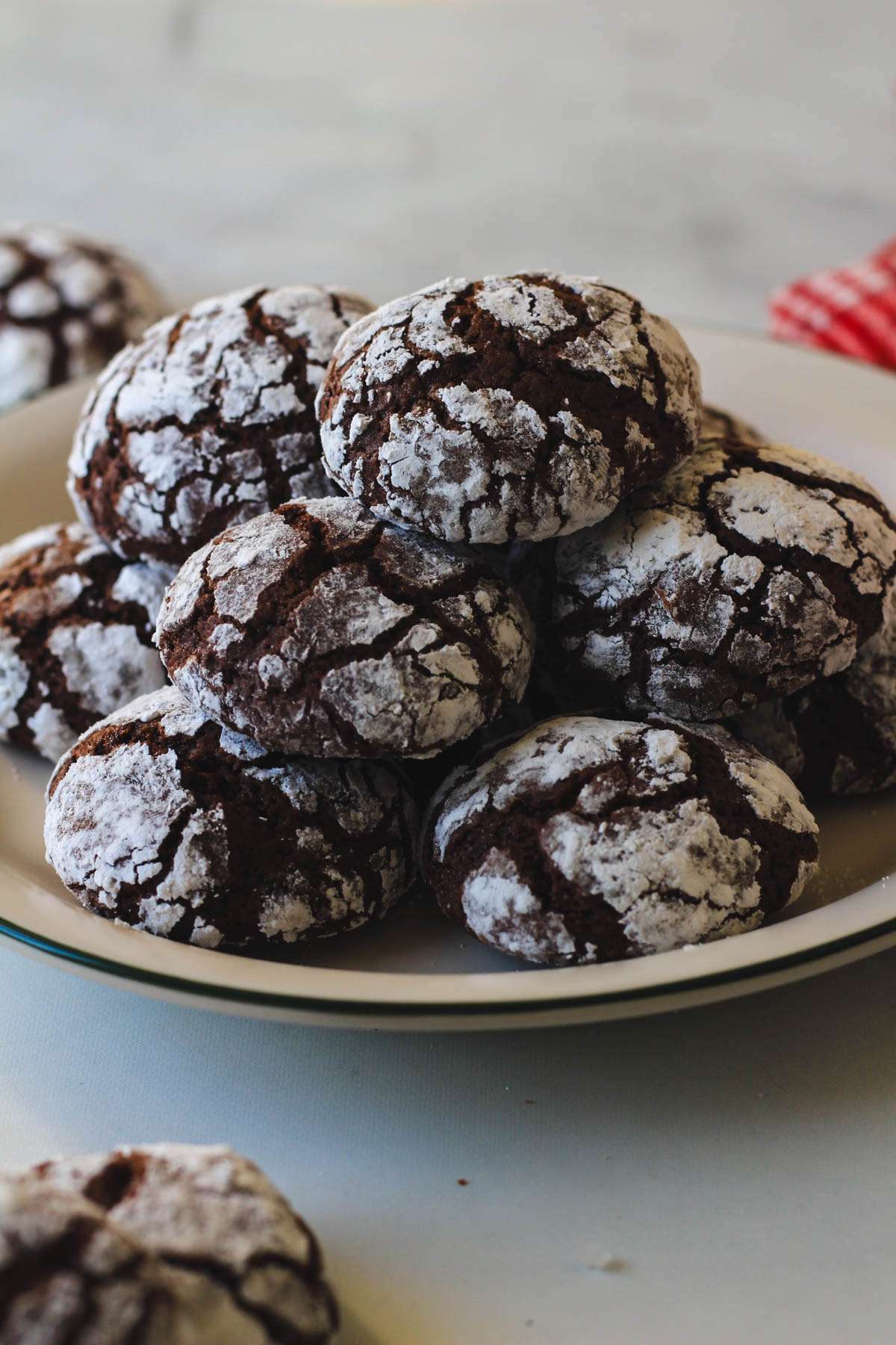 Dairy-free chocolate crinkle cookies on a green rimmed white plate on a white counter.