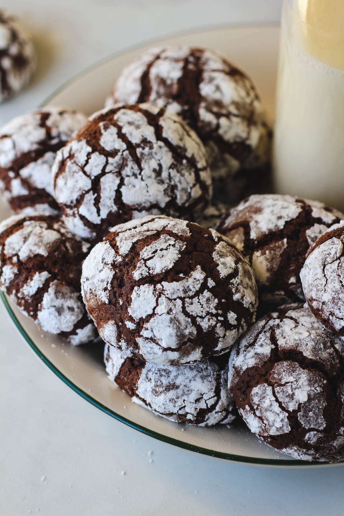 Dairy-free chocolate crinkle cookies on a white plate with a bottle of oat milk.