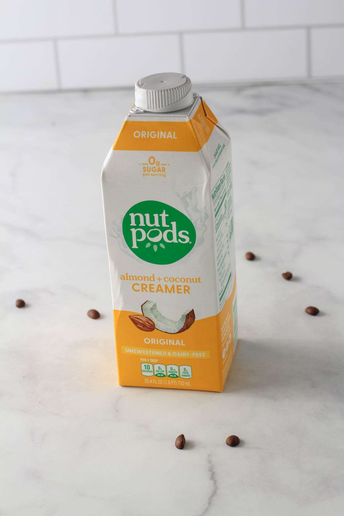 A carton of Nut Pods vegan coffee creamer on a white counter.