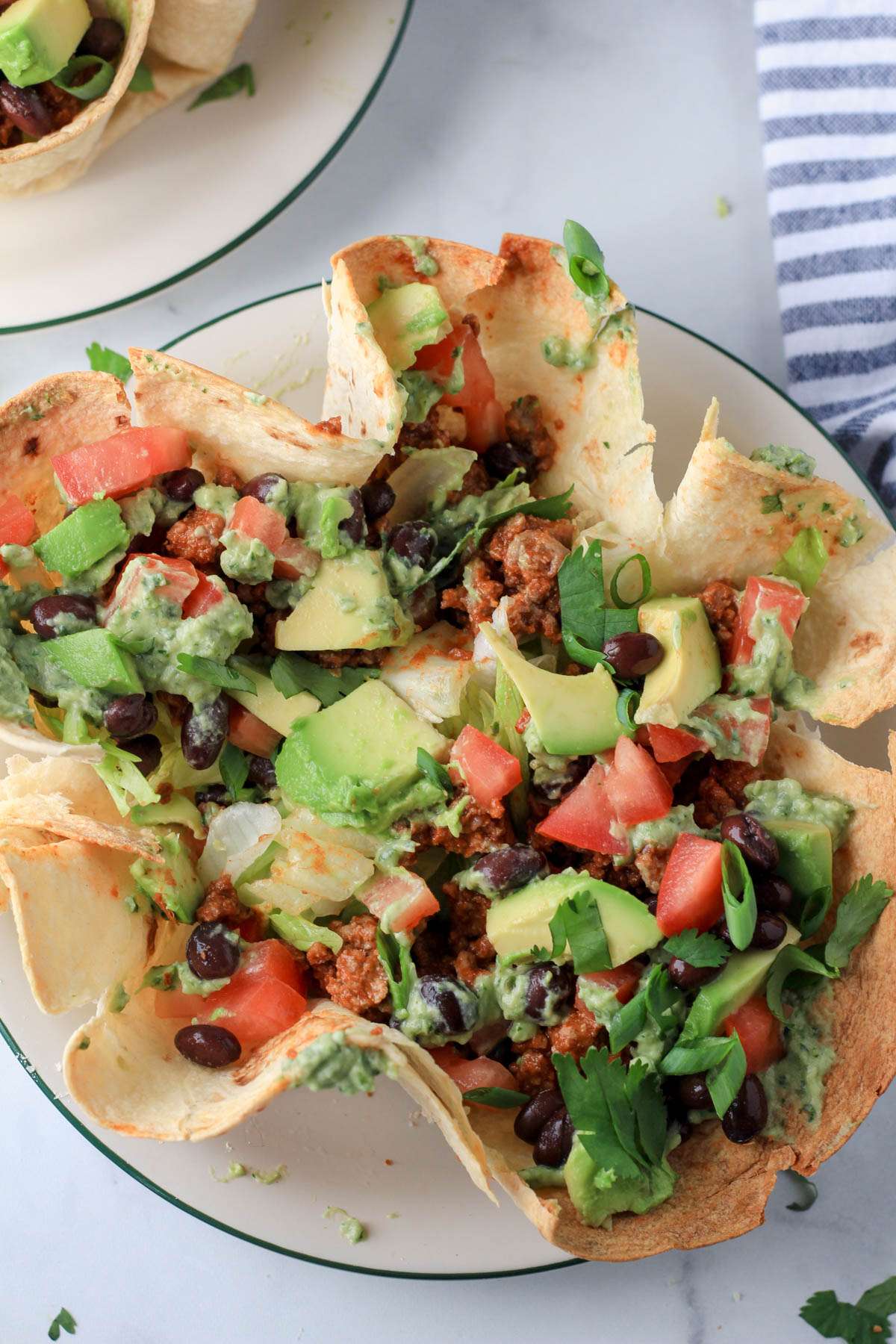 A top down photo of a dairy-free taco salad on a white plate with a green rim.