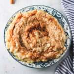 A close up of vegan oat milk rice pudding topped with cinnamon sugar on a white counter.
