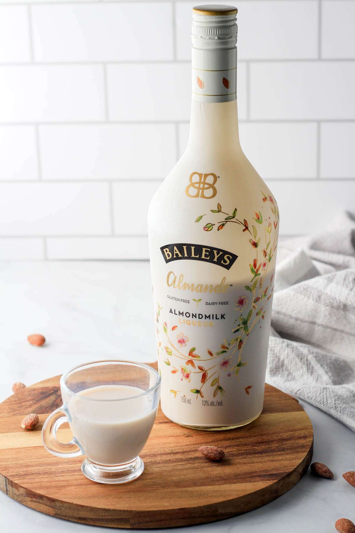 A wooden tray with a bottle of Almande and a small glass filled with Bailey's Almande.