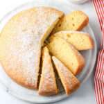 A marble cake stand with sliced dairy-free yogurt cake dusted with powdered sugar.