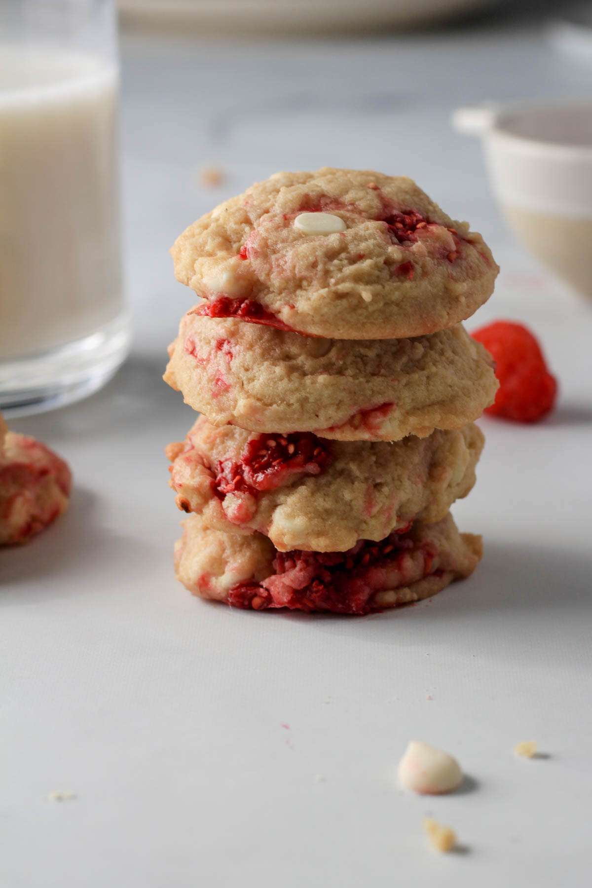 A stack of four raspberry white chocolate chip cookies on a white counter.