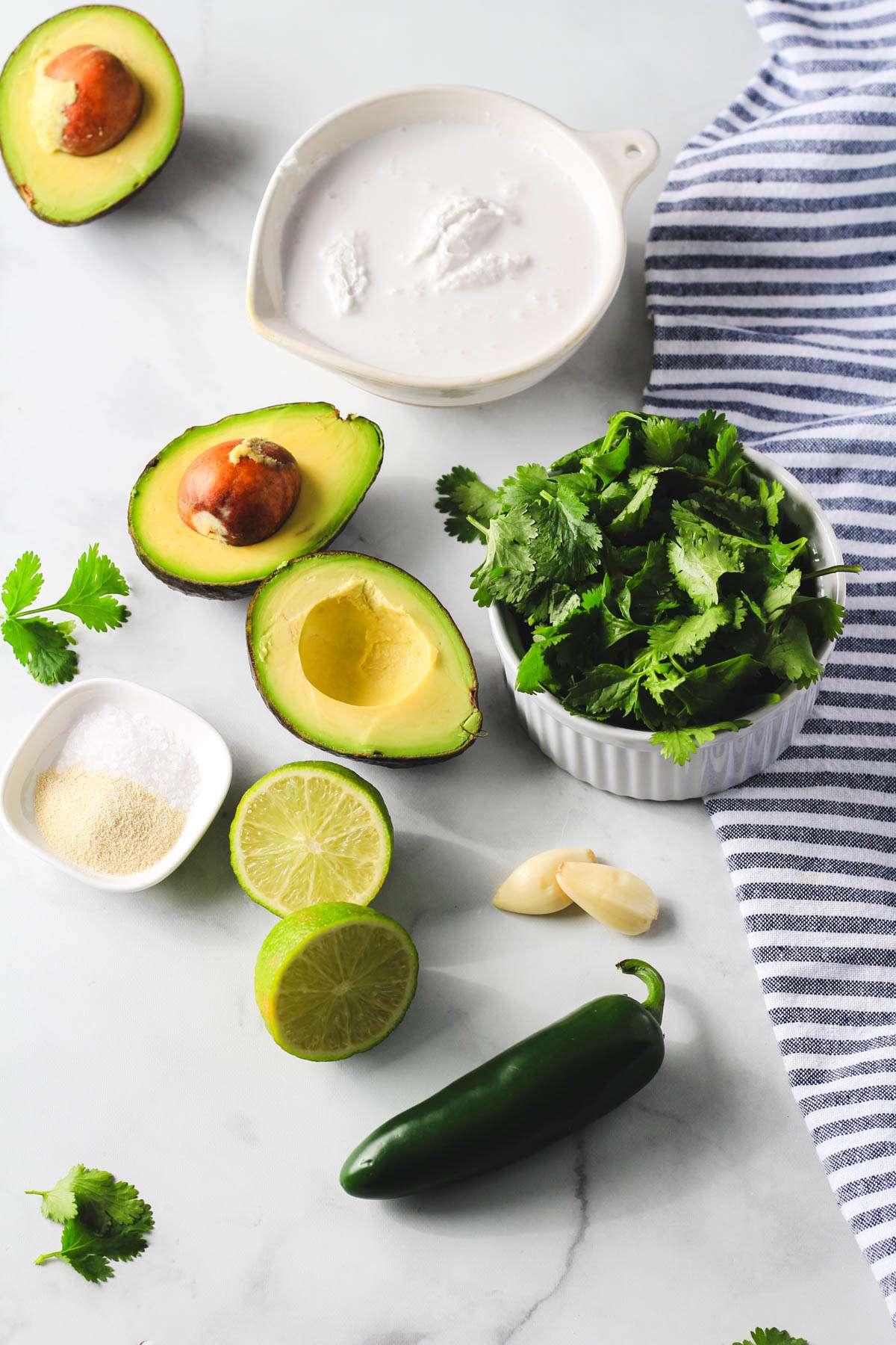 Ingredients for vegan avocado cilantro lime crema on a white counter.