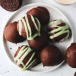A small white plate topped with chocolate coated vegan Irish cream Oreo truffles.