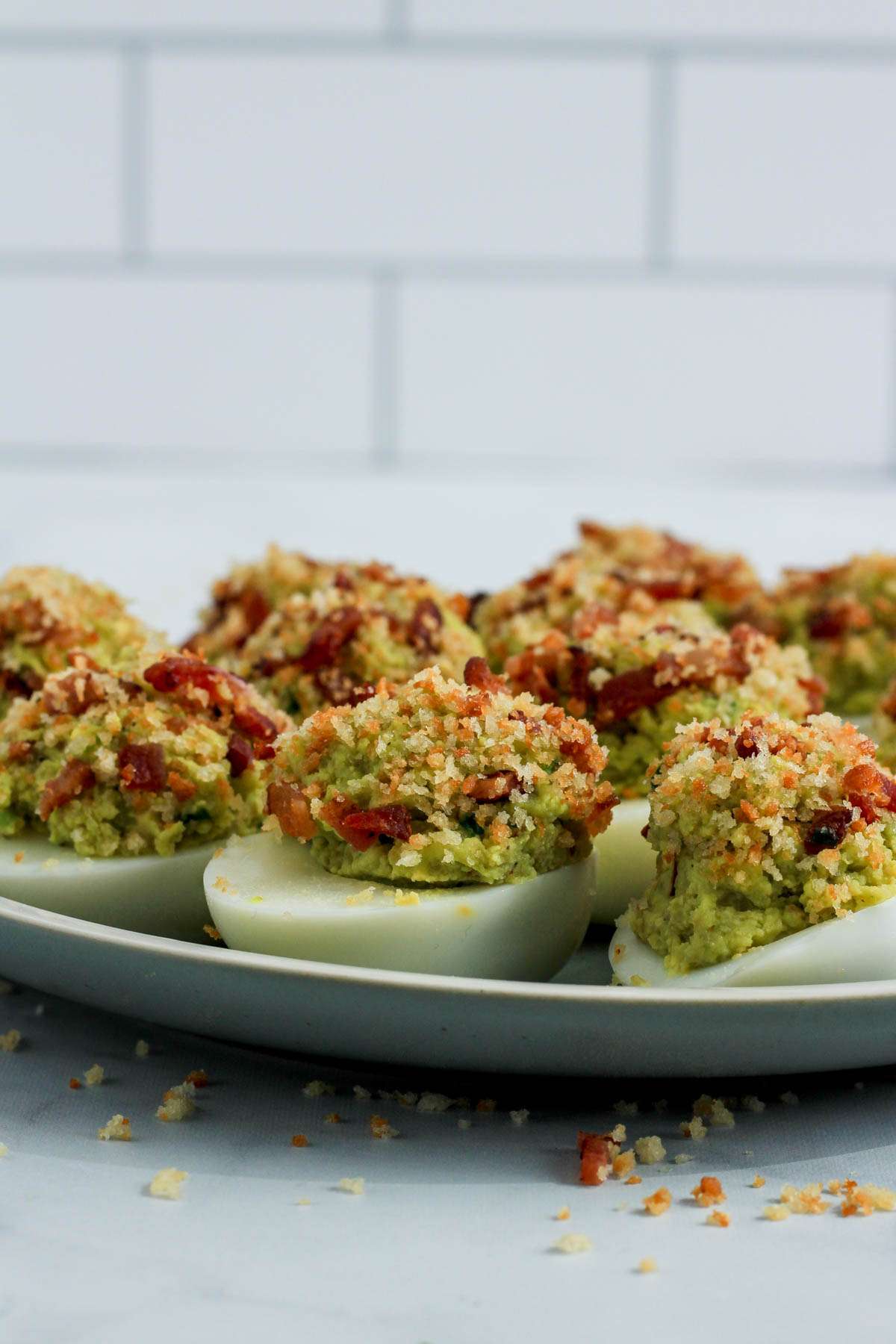 Bacon and panko avocado deviled eggs from the side on a green plate.