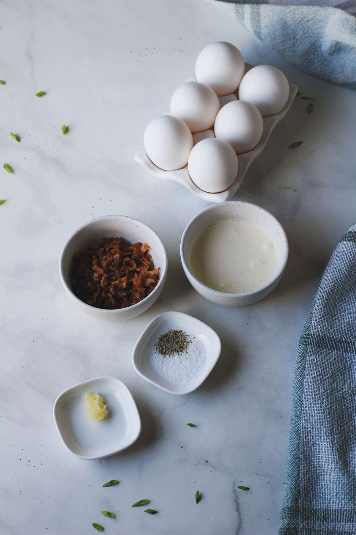 Ingredients for dairy-free egg bites on a white counter with a blue towel.