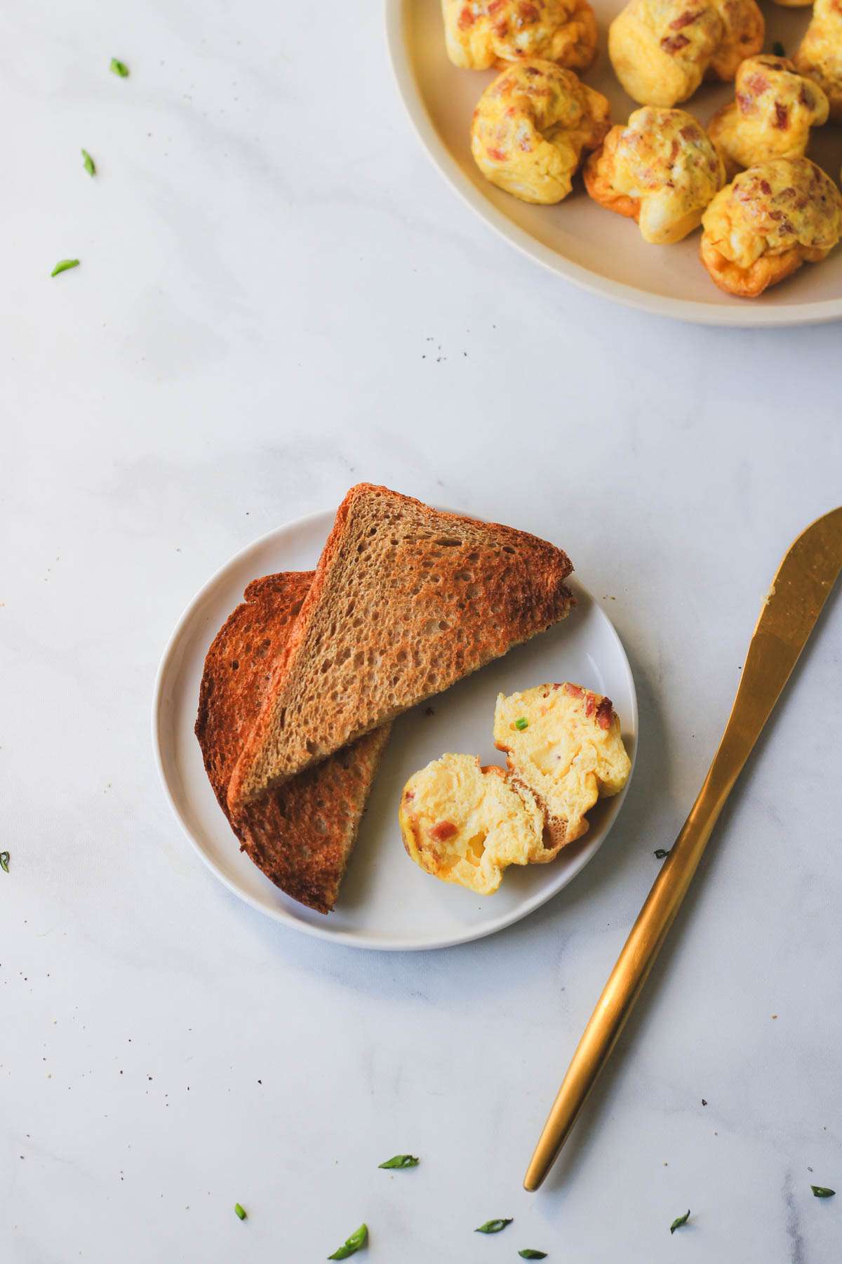 A small white plate with one air fryer egg bite sliced open next to two slices of toast.