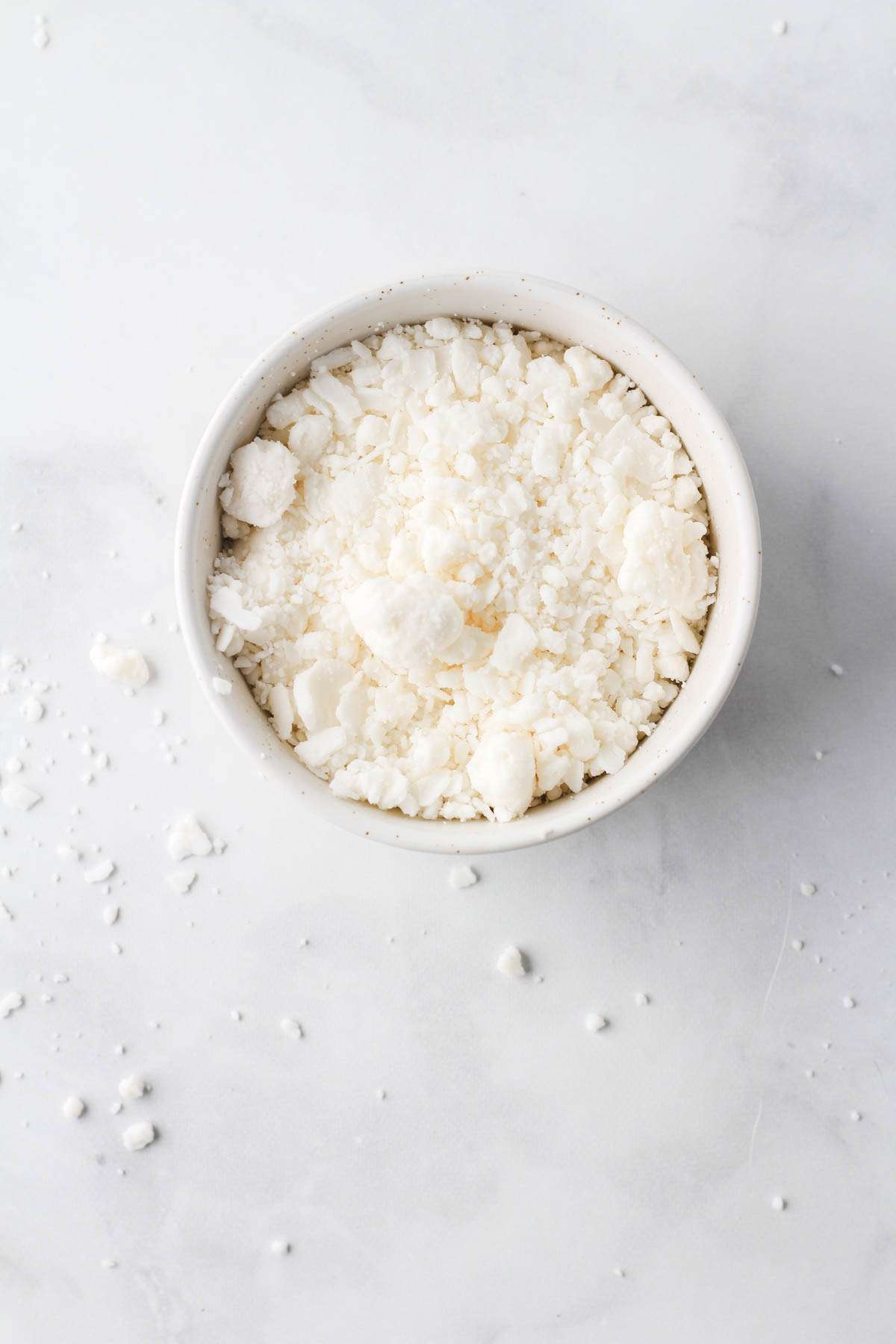 A small white bowl on a white counter filled with Follow Your Heart Feta Cheese Crumbles.