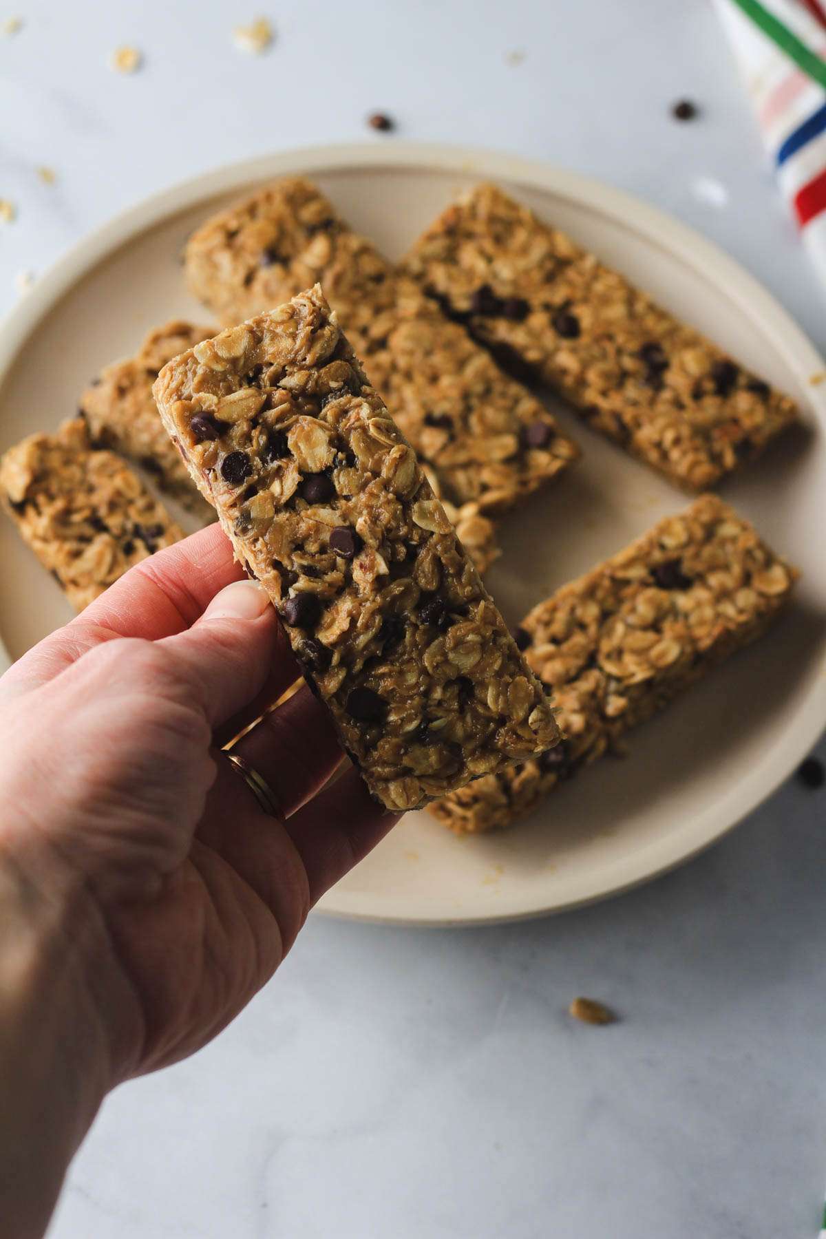 A hand holding a chocolate chip studded nut-free granola bar.