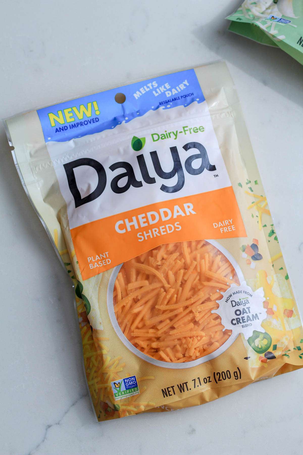 A package of Daiya Cheddar shreds on a white counter.