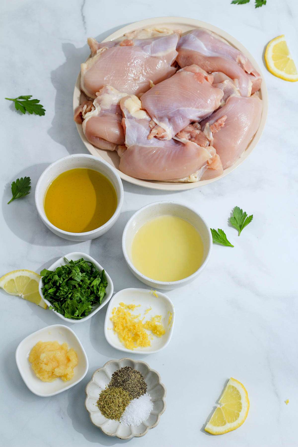 Ingredients for Greek marinated chicken thighs on a white counter.