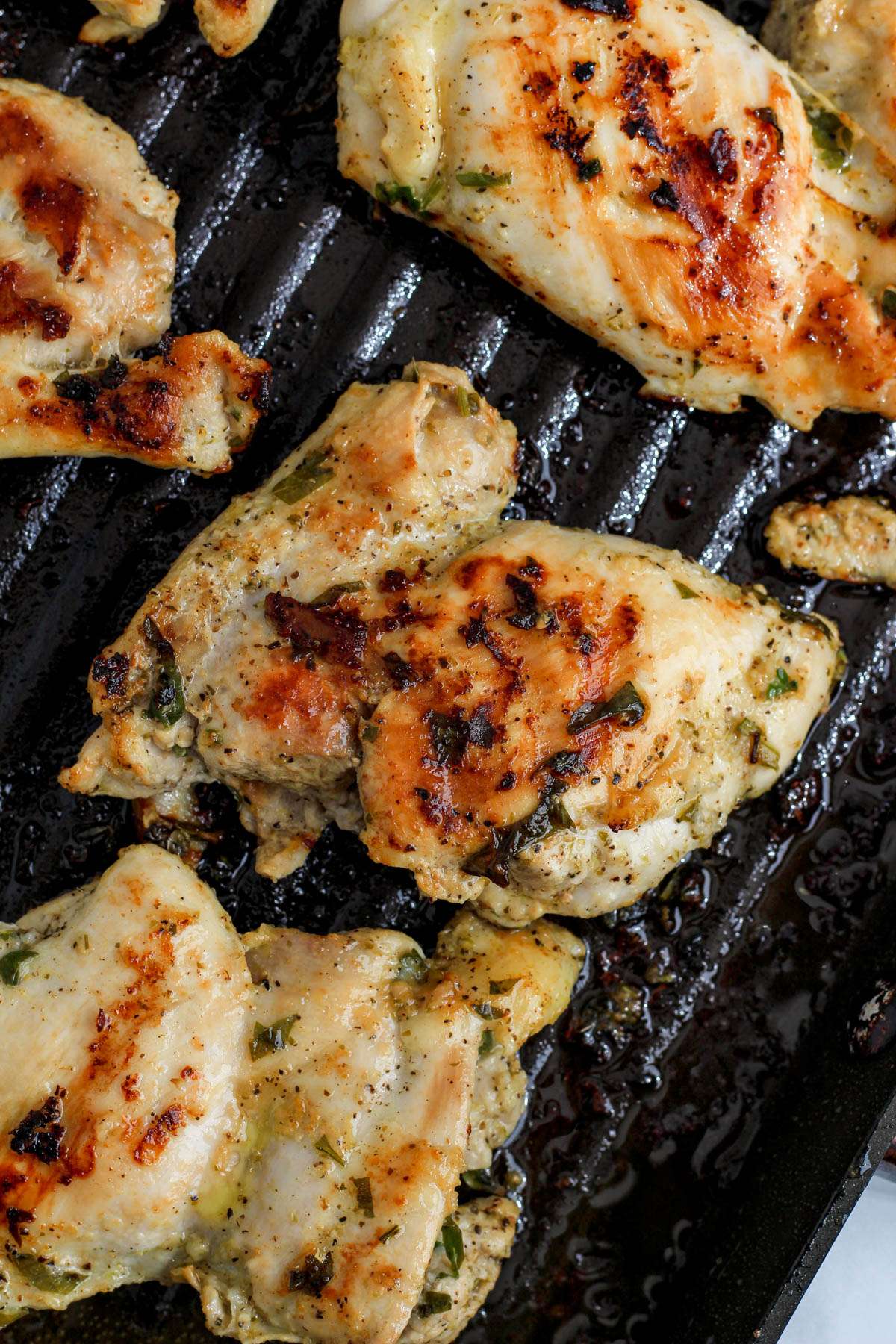 A close up of a marinated chicken thigh on a grill pan.