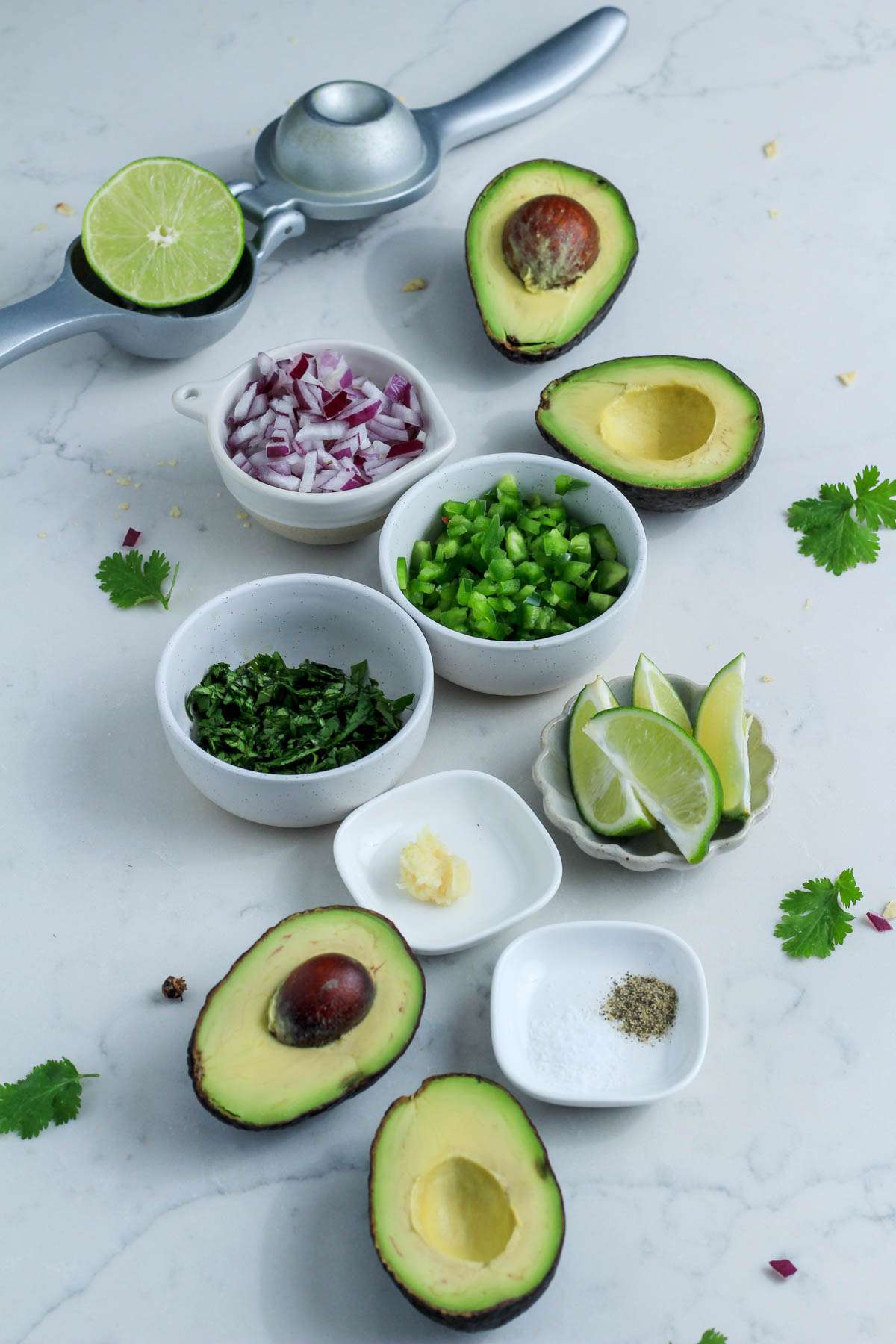 Ingredients for homemade guacamole on a white counter.