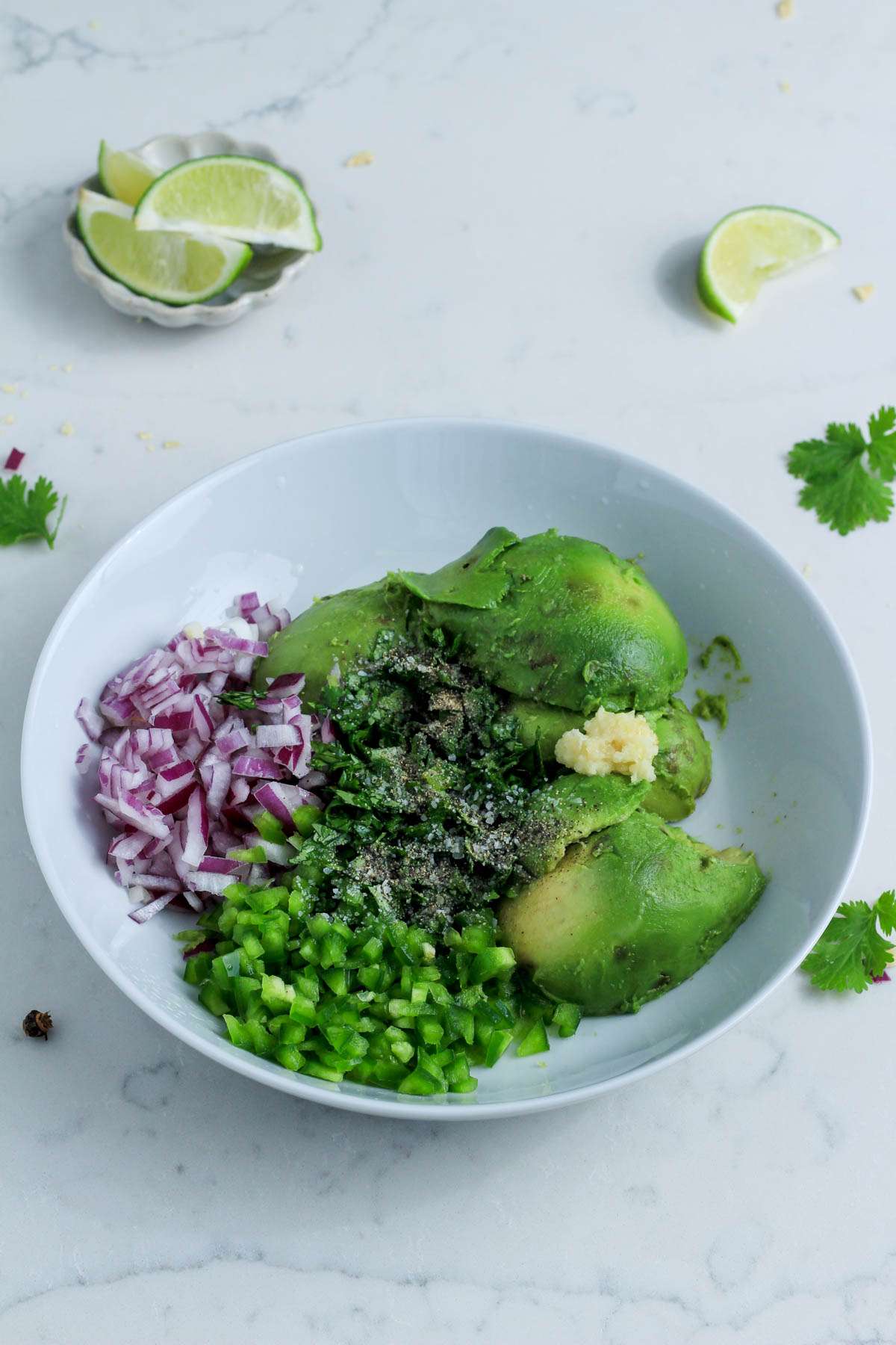 A white bowl with the ingredients for homemade guacamole before mixing together.