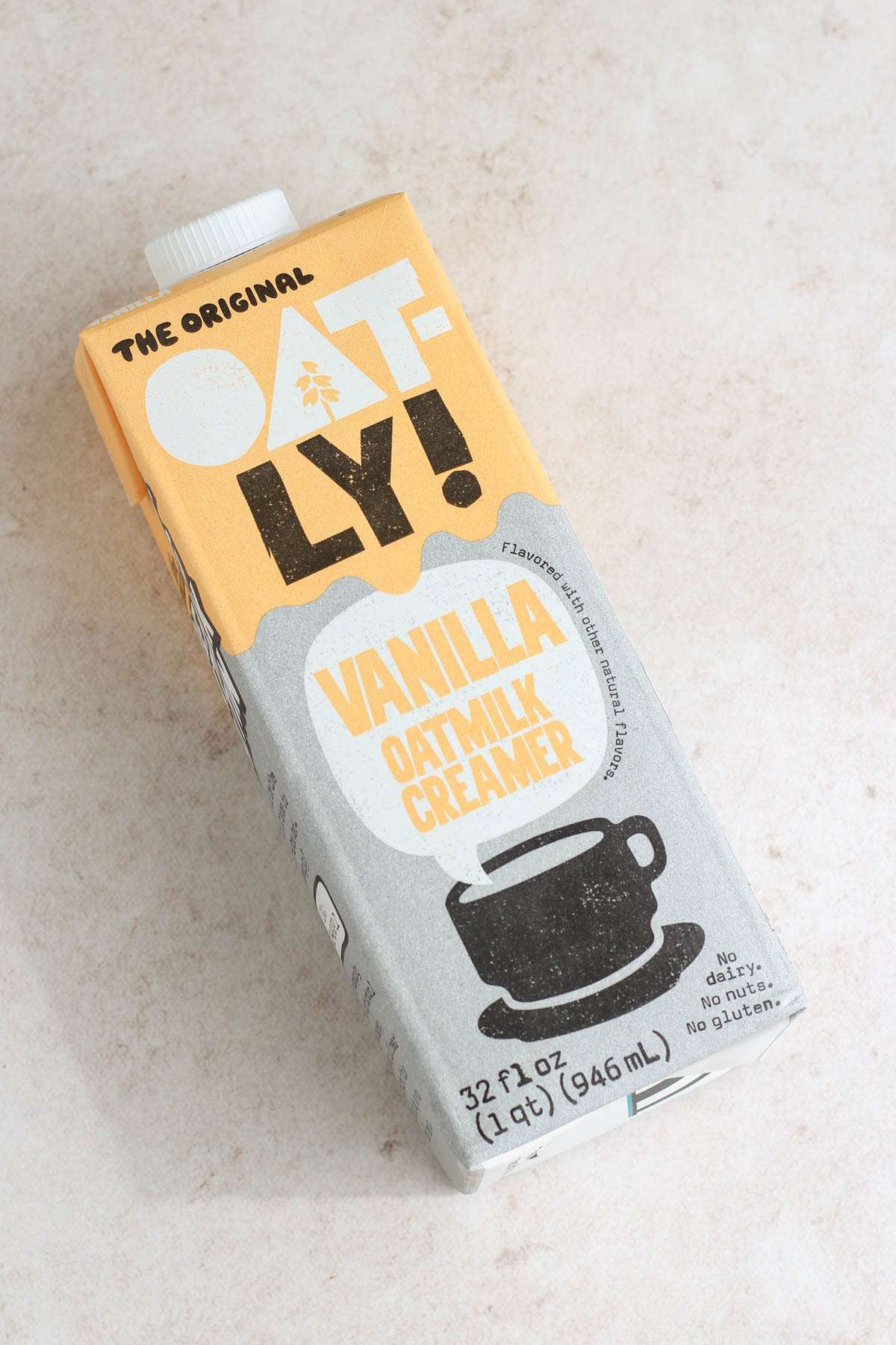 A carton of Oatly coffee creamer on a tan counter.