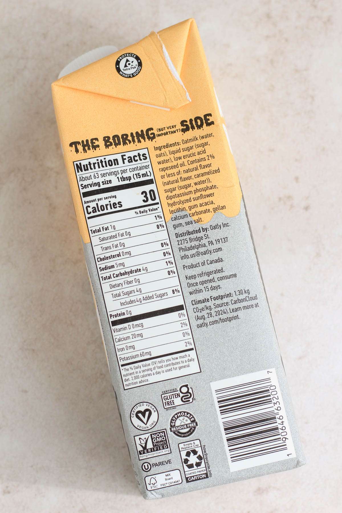 The nutritional label of a carton of Oatly coffee creamer on a tan counter.
