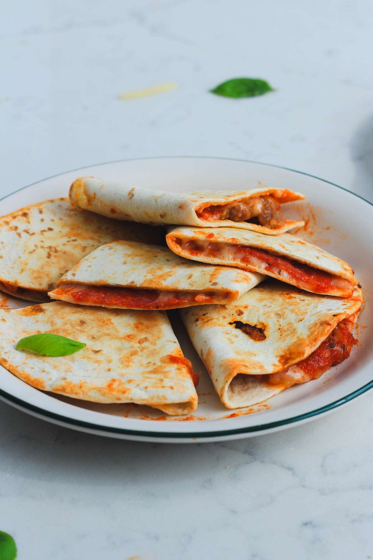 A small white plate topped with various dairy-free pizza quesadillas.