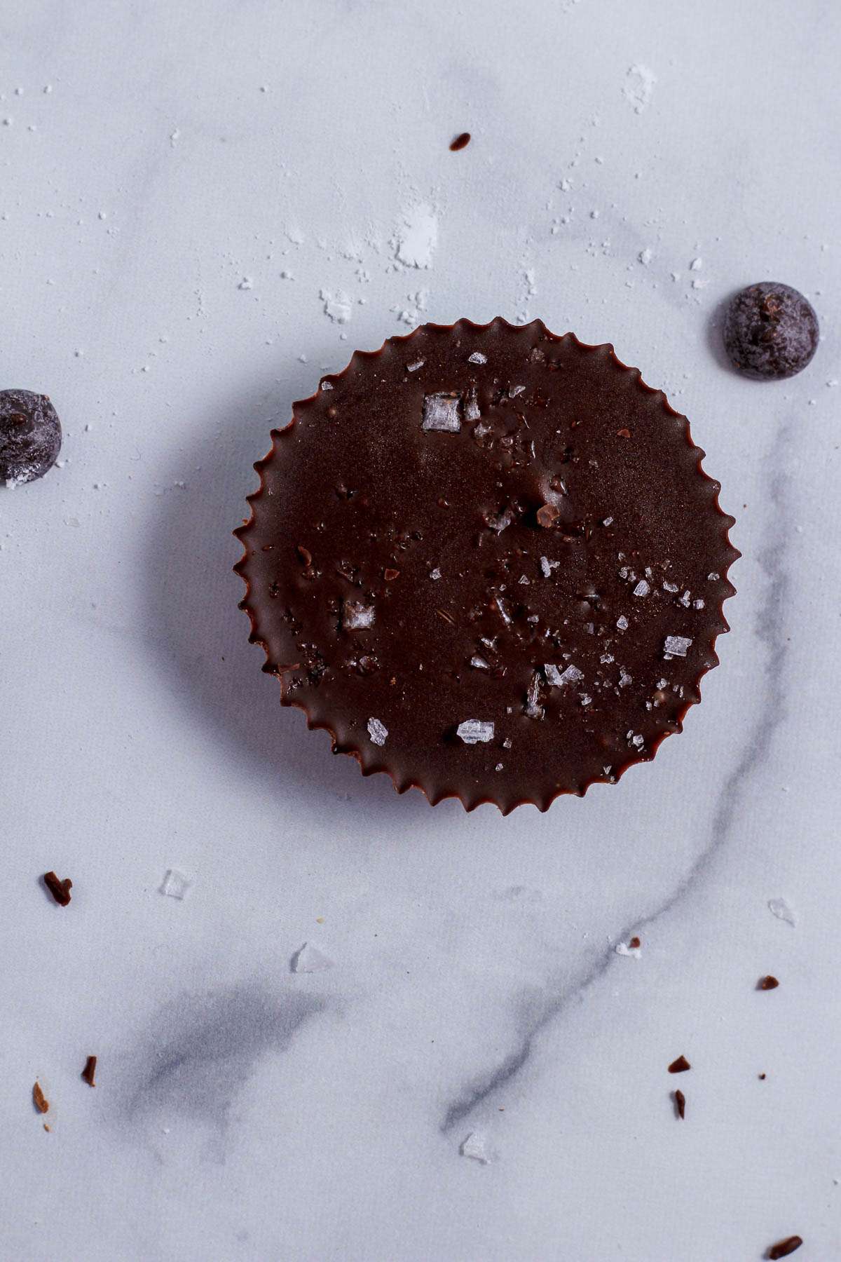 A dark chocolate vegan peanut butter cup on a grey and white counter.