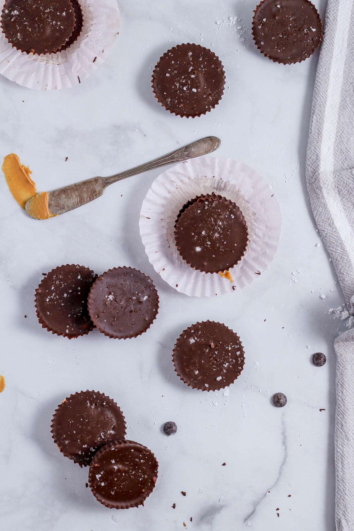 A smattering of plant-based peanut butter cups on a counter with chocolate and peanut butter spilled about.