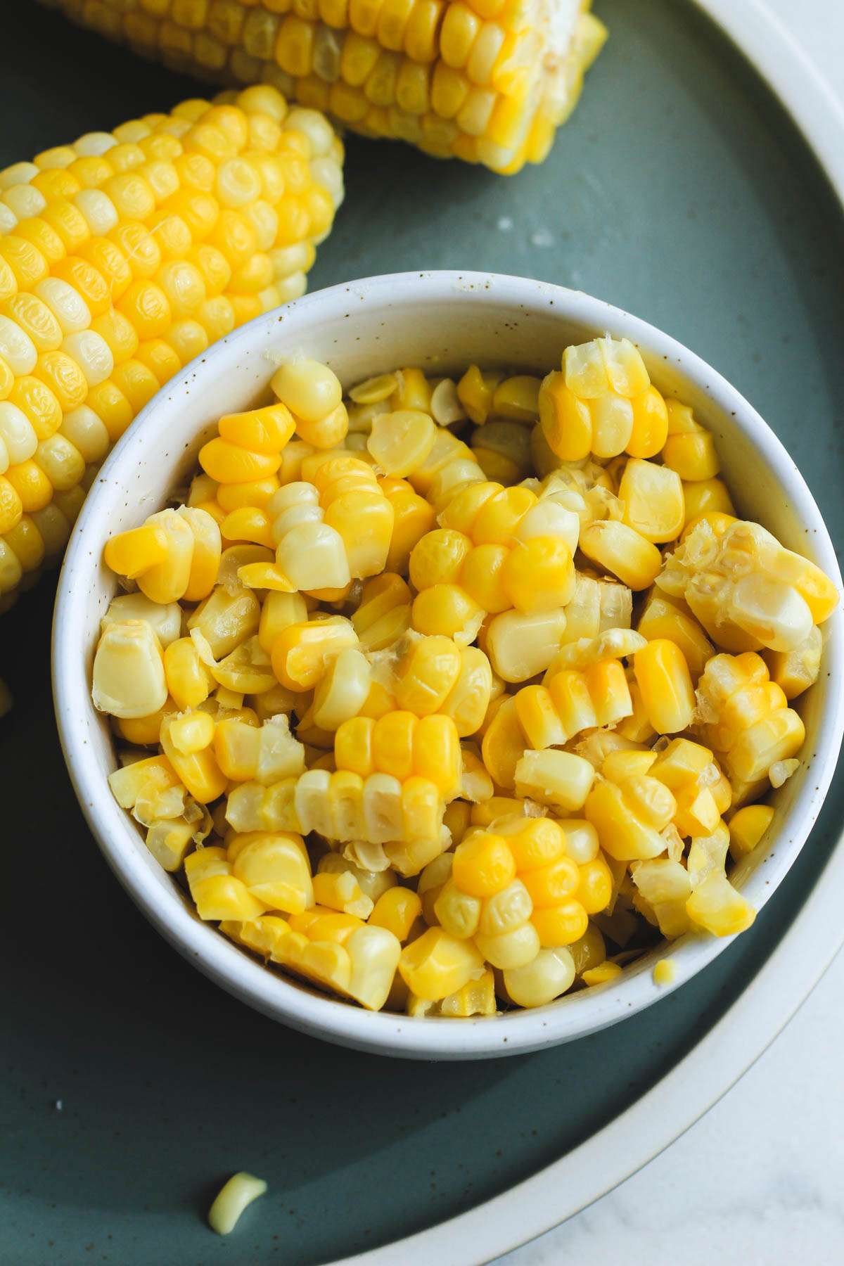 A small white bowl filled with corn kernels cut off a corn cob from the microwave.