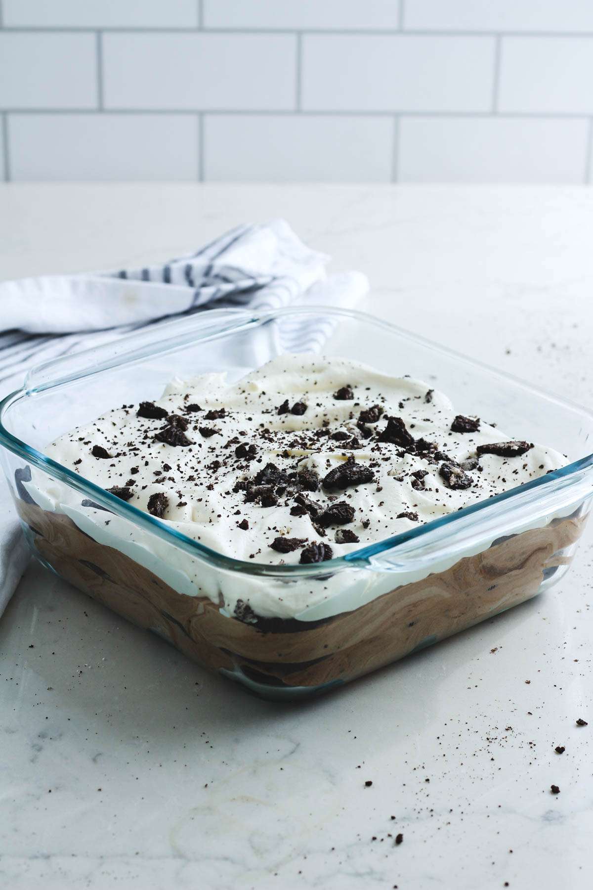 Oreo ice box cake on a white counter with crushed Oreos on top.