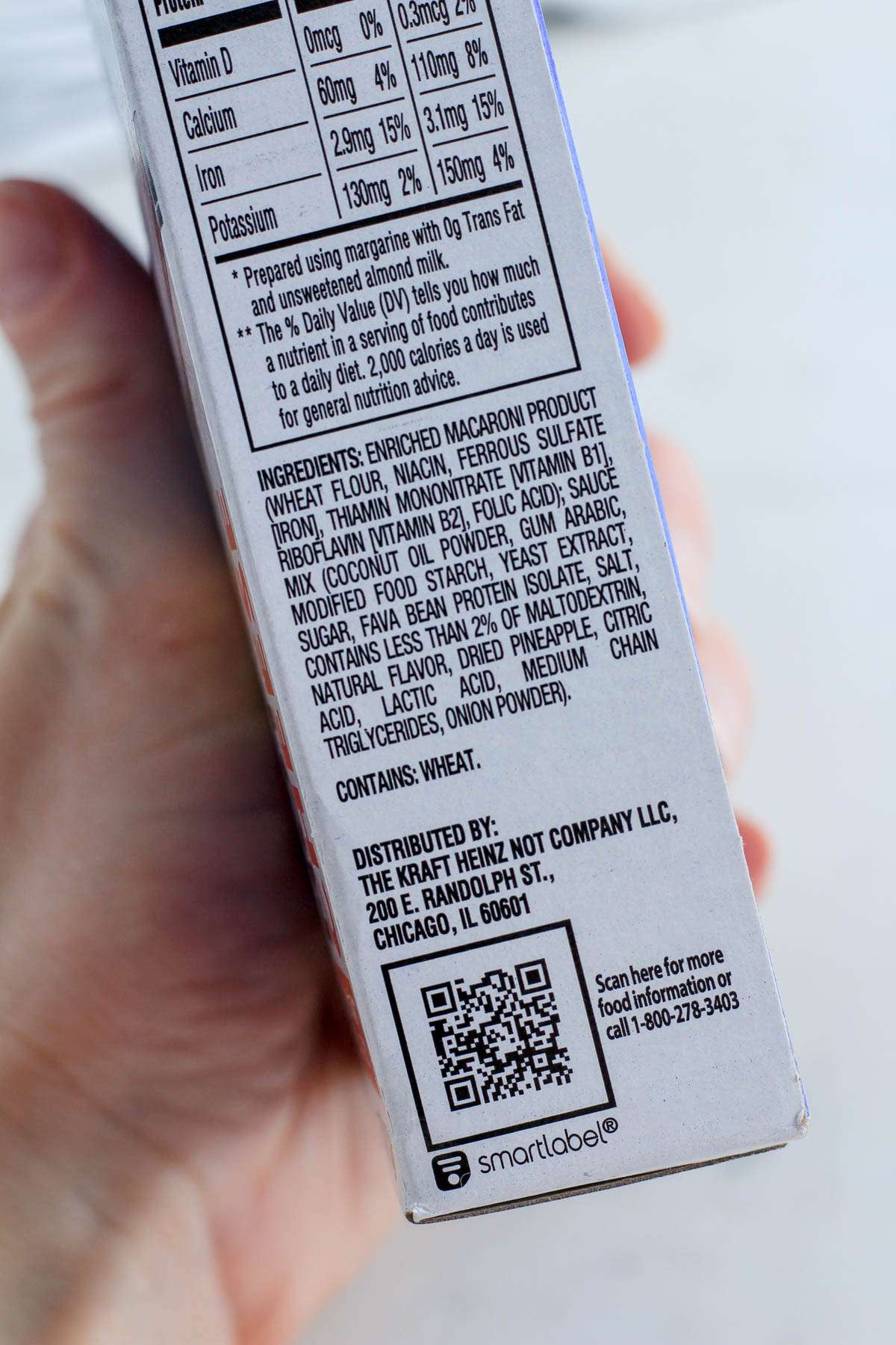 A hand holding up the ingredients section of the plant based mac and cheese box.