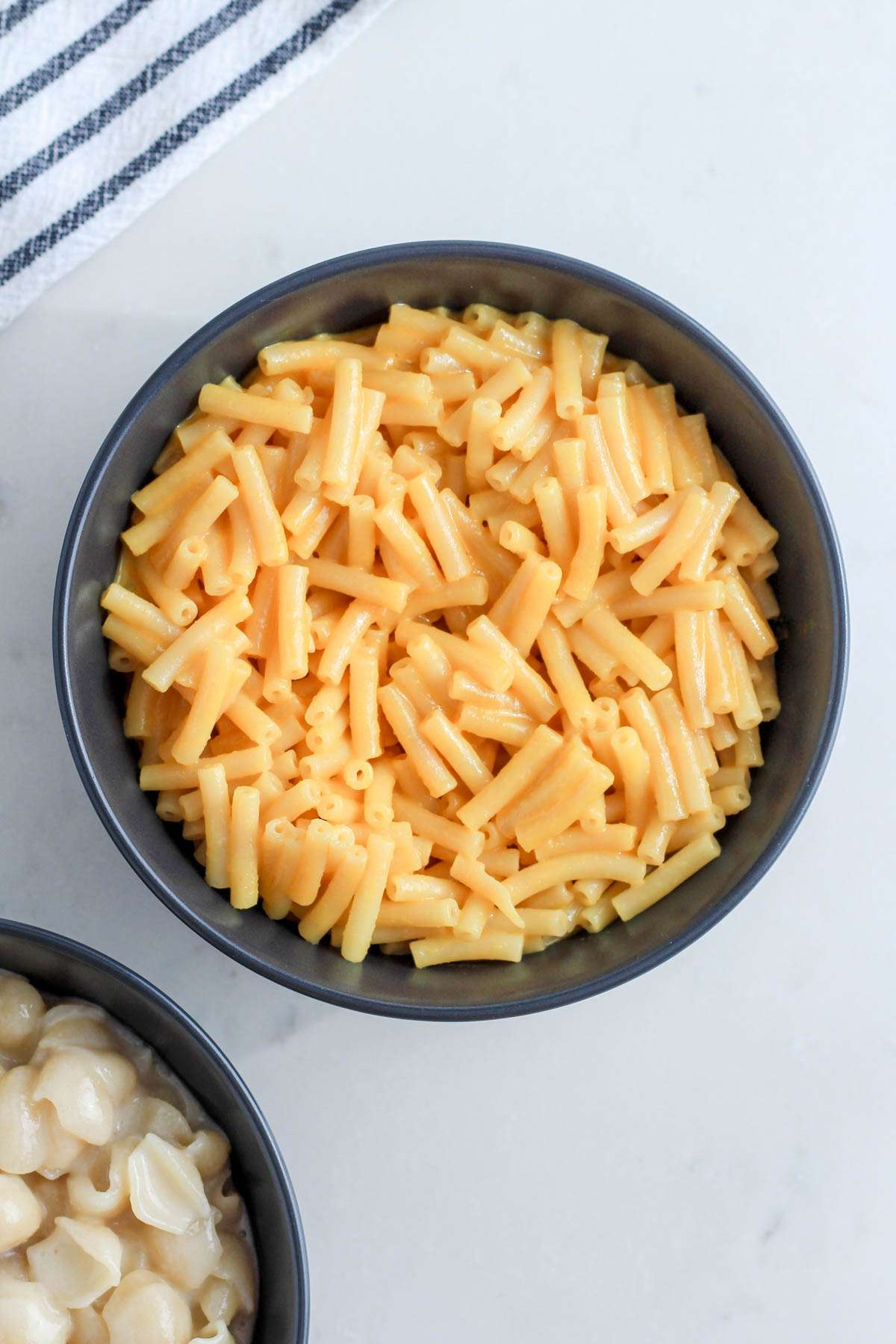 A photo of the original mac and cheese flavor in a bowl next to the white cheddar style flavor bowl.