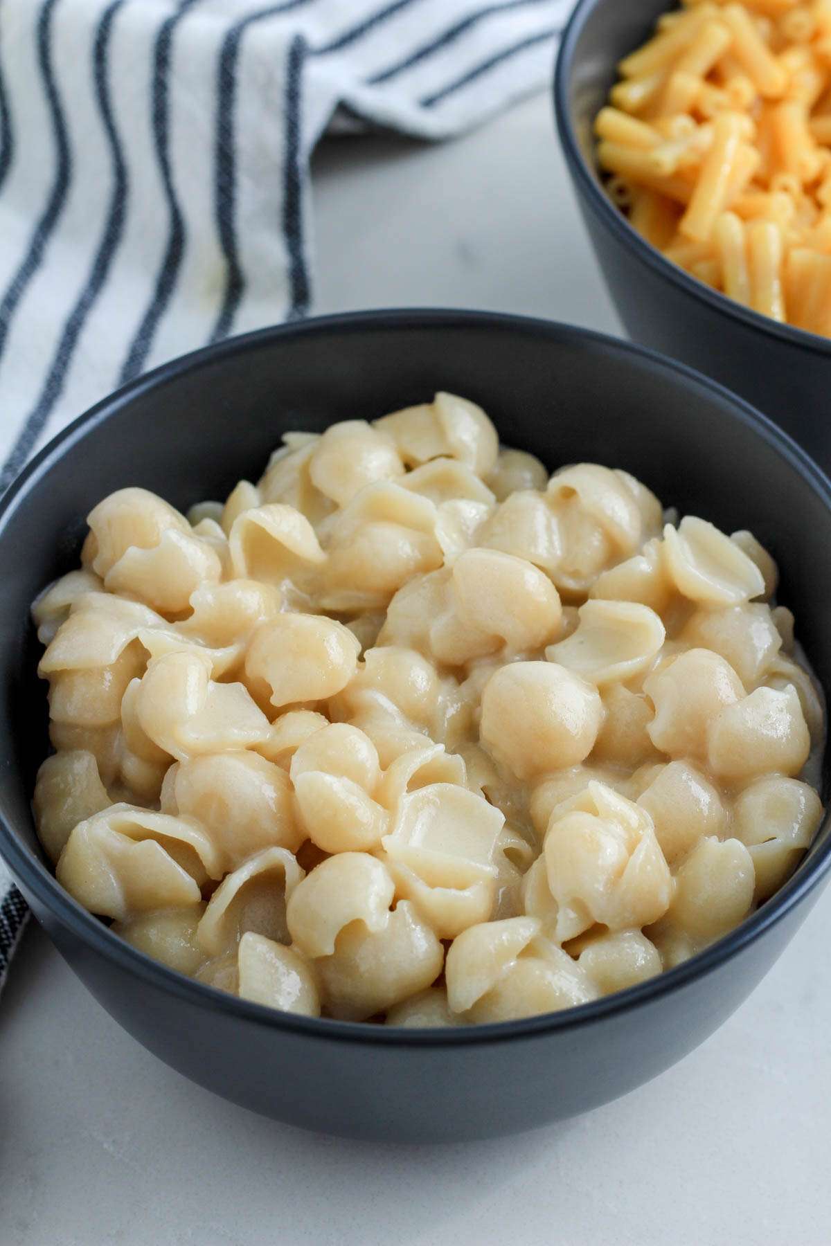 A blue bowl of Plant Based Kraft Mac and Cheese in front of a bowl of the original flavor plant-based mac and cheese.