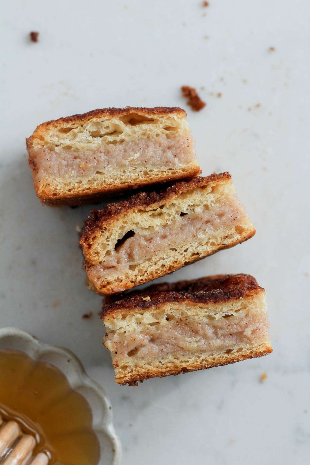 Three sopapilla cheesecake bars turned on the side to show the filling on a white counter.