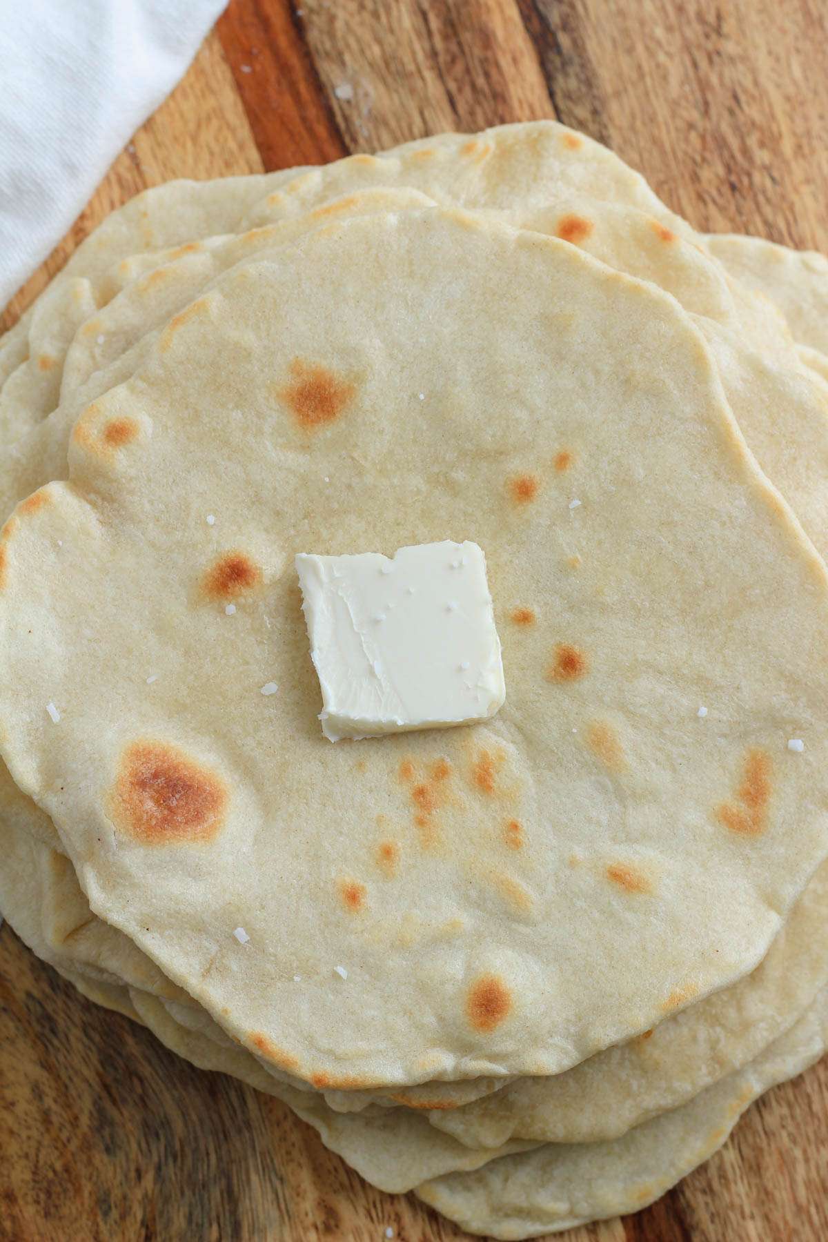 A stack of vegan flour tortillas with a small pad of butter on the top of the stack.