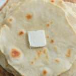 A small pad of vegan butter on top of a stack of vegan flour tortillas.