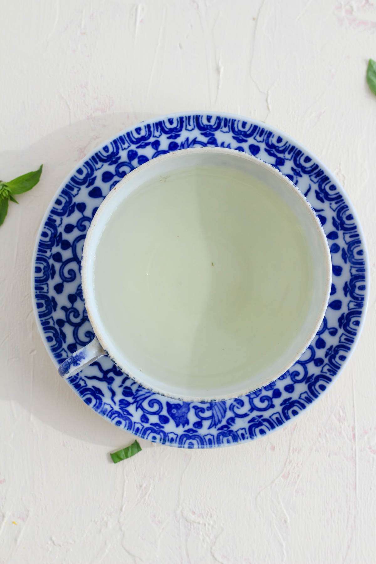 A white and blue tea cup with fresh basil tea.