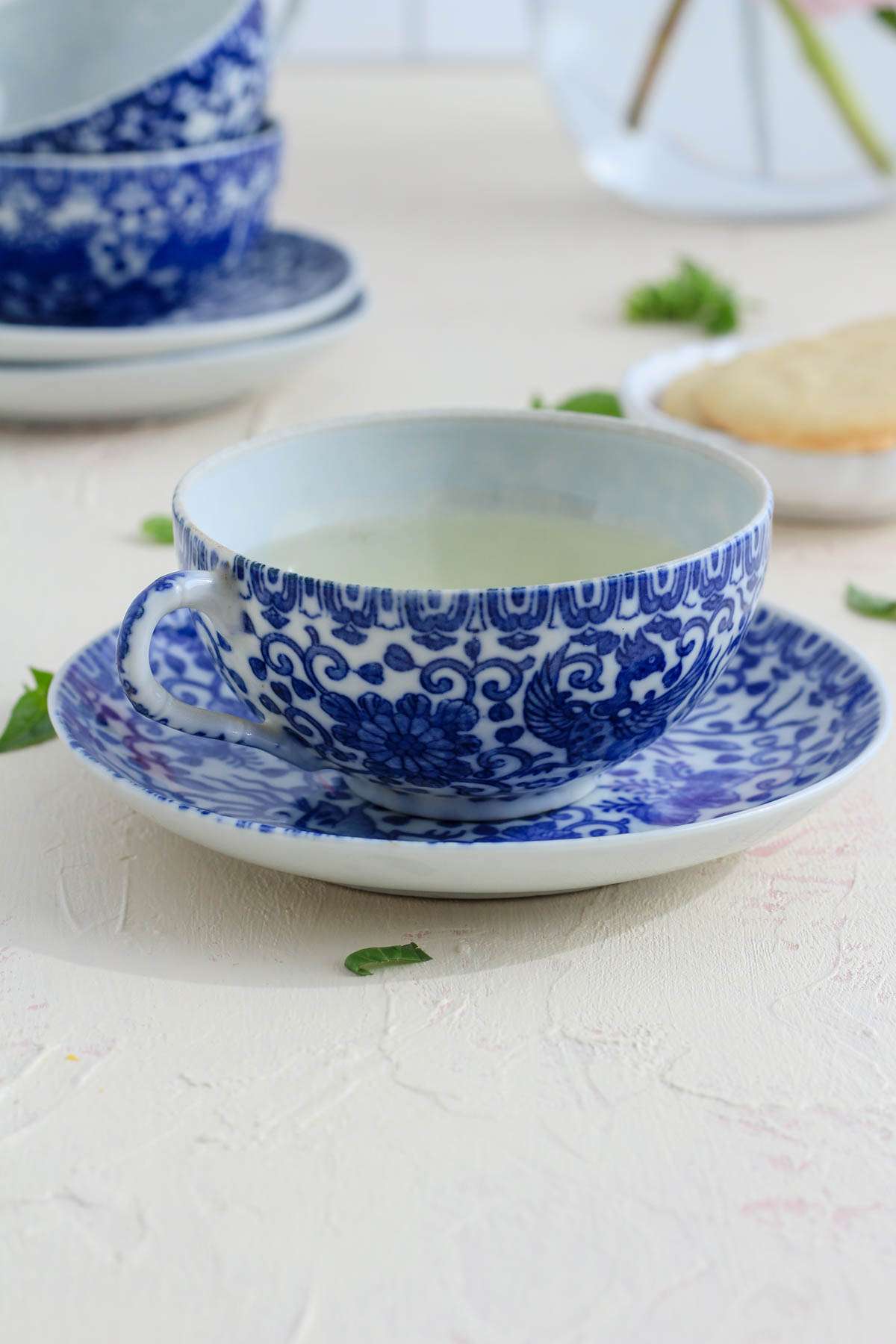 Homemade basil tea made with fresh basil leaves in a white and blue tea cup.