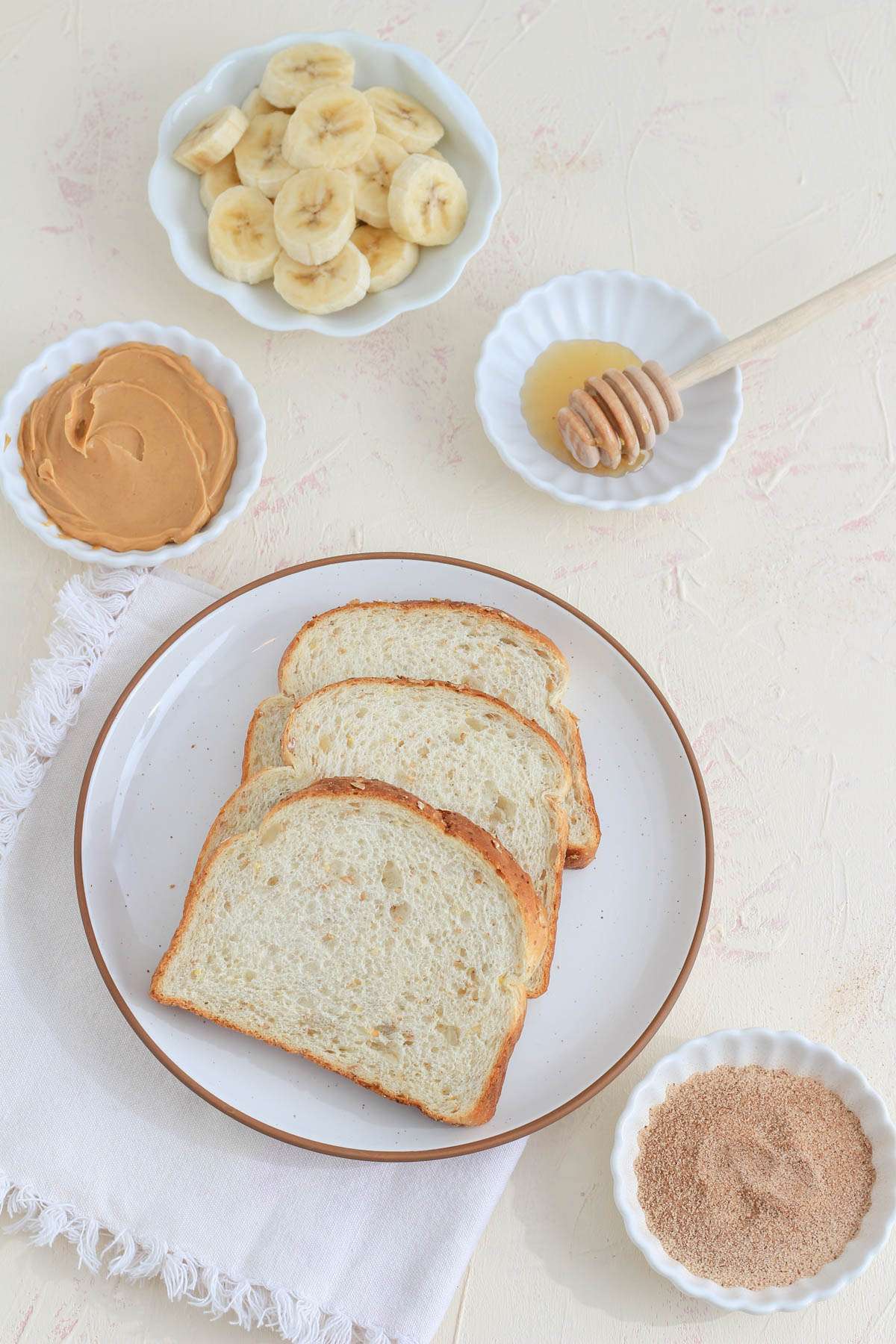Ingredients for peanut butter banana toast on a white counter.