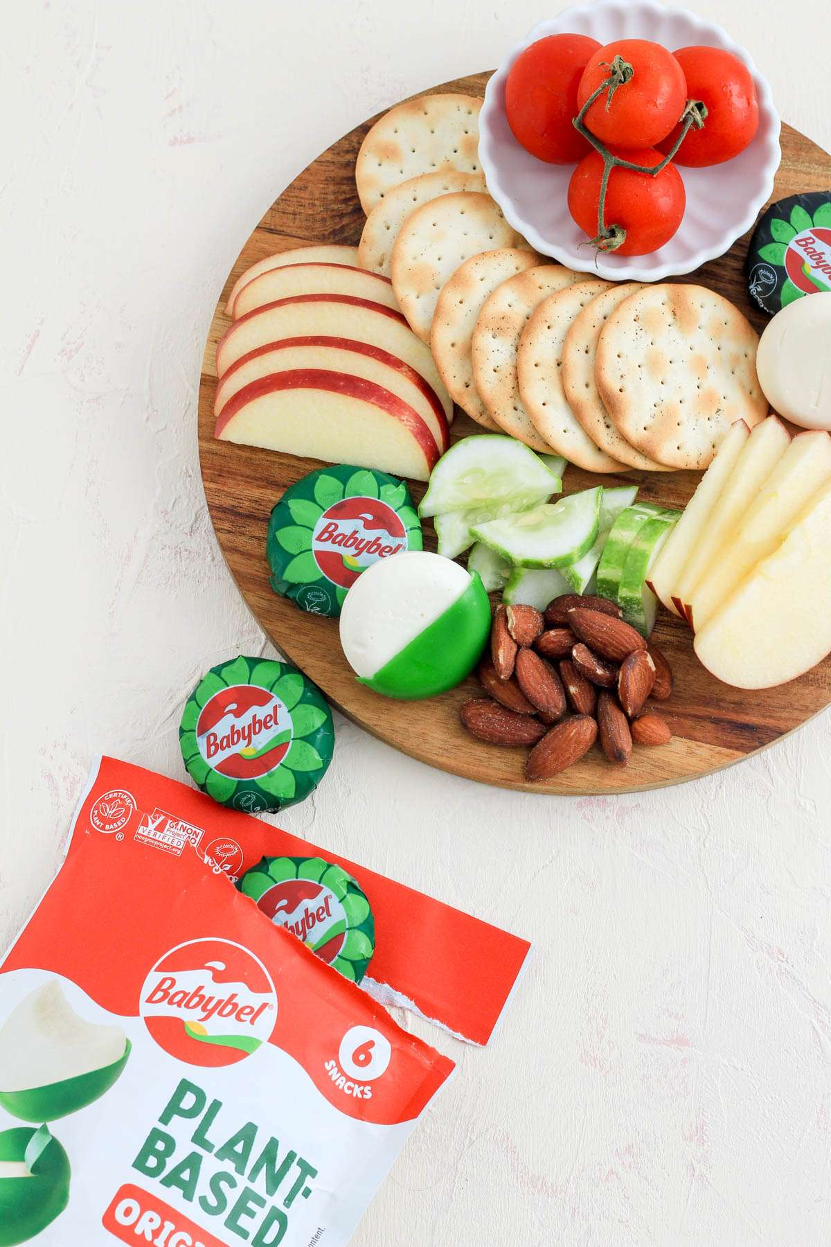 A package of babybel dairy-free cheese wheels open and leading to the vegan cheese board in the top right corner.