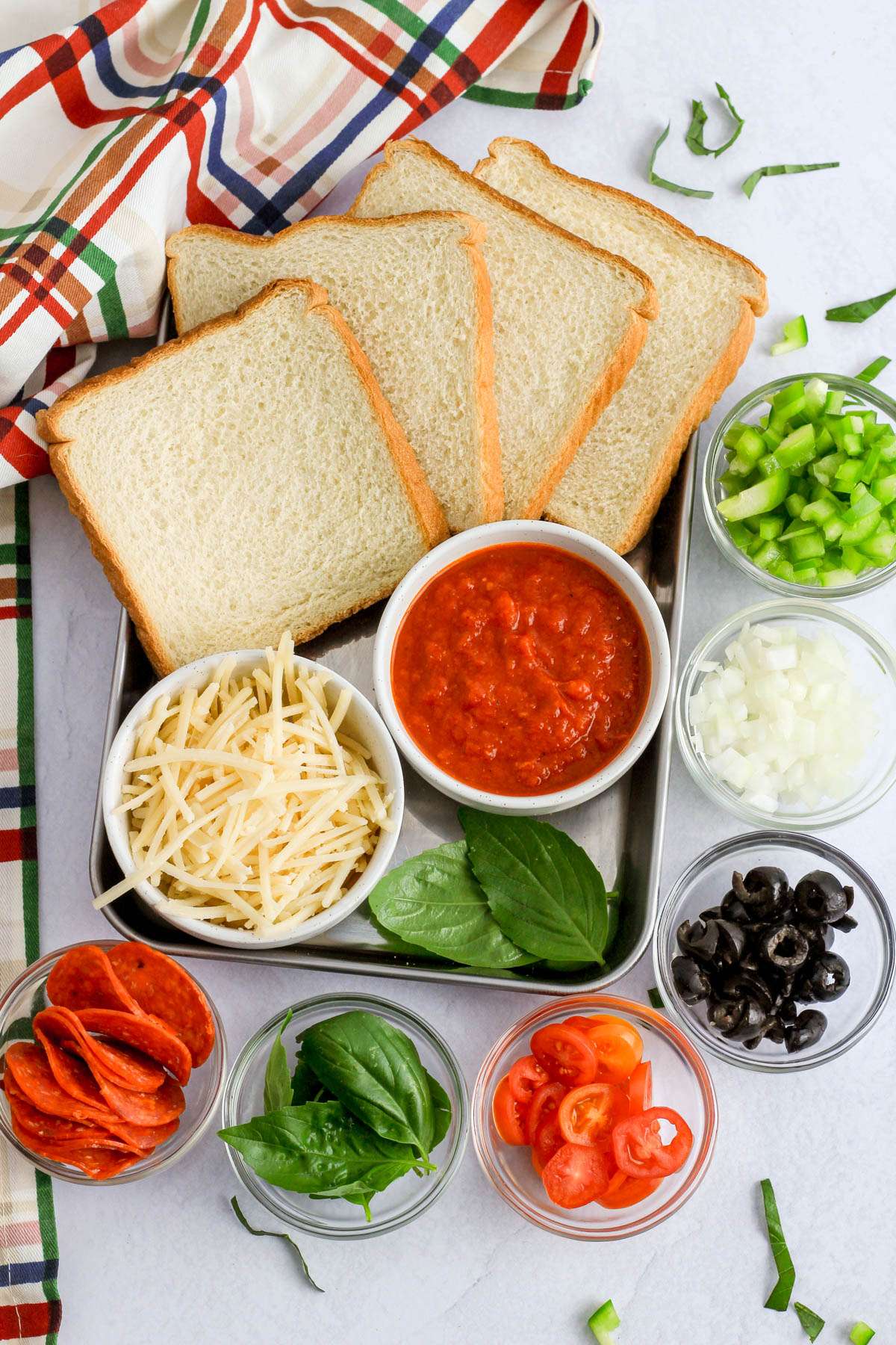 Ingredients for pizza toast on a grey counter.
