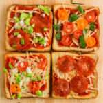 A close up of four slices of dairy-free pizza toast on a wooden counter.