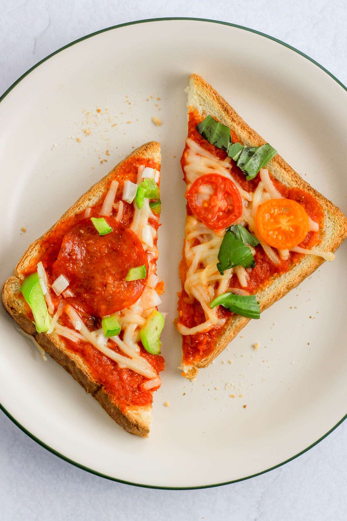 A small white plate with a green rim topped with two slices of dairy-free pizza toast.