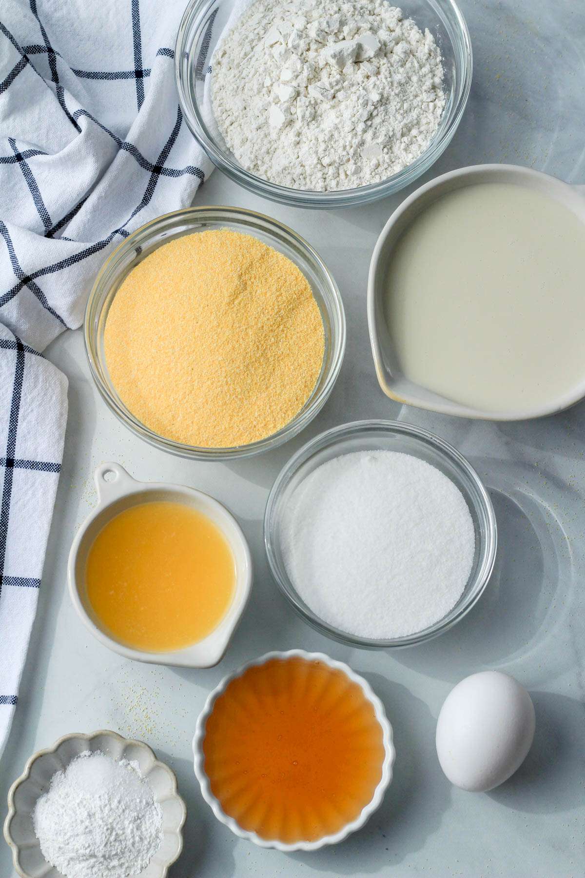 Ingredients for gluten-free dairy-free cornbread on a white counter next to a blue and white dish towel.