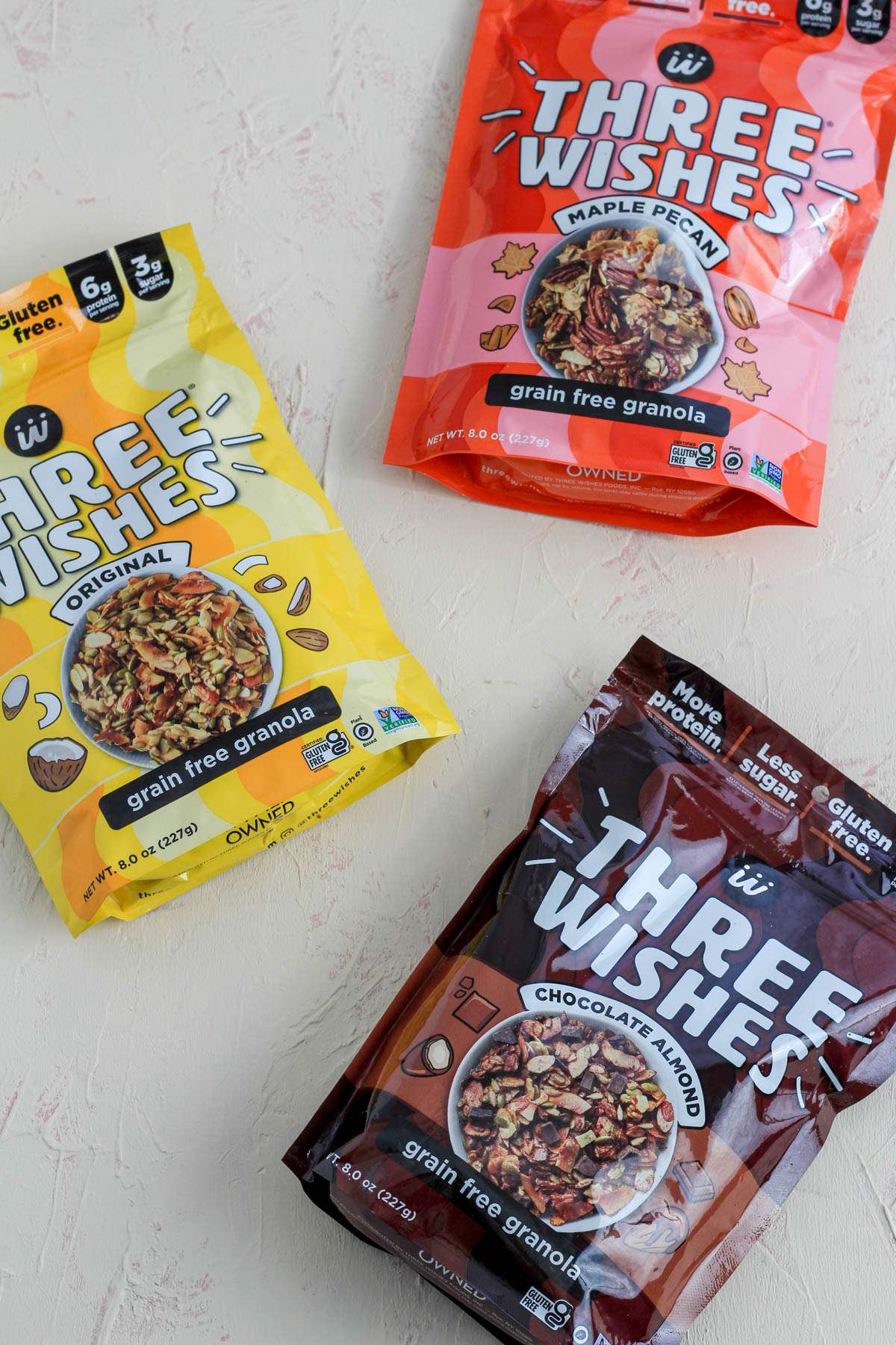 Three packages of Three Wishes grain free granola on a cream counter.