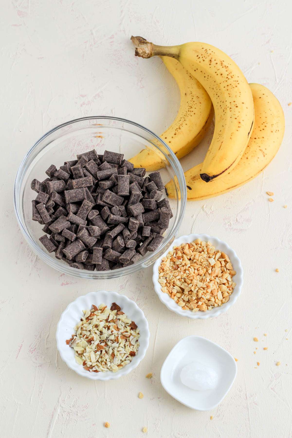 Ingredients for dairy-free chocolate dipped banana bites on a white counter.