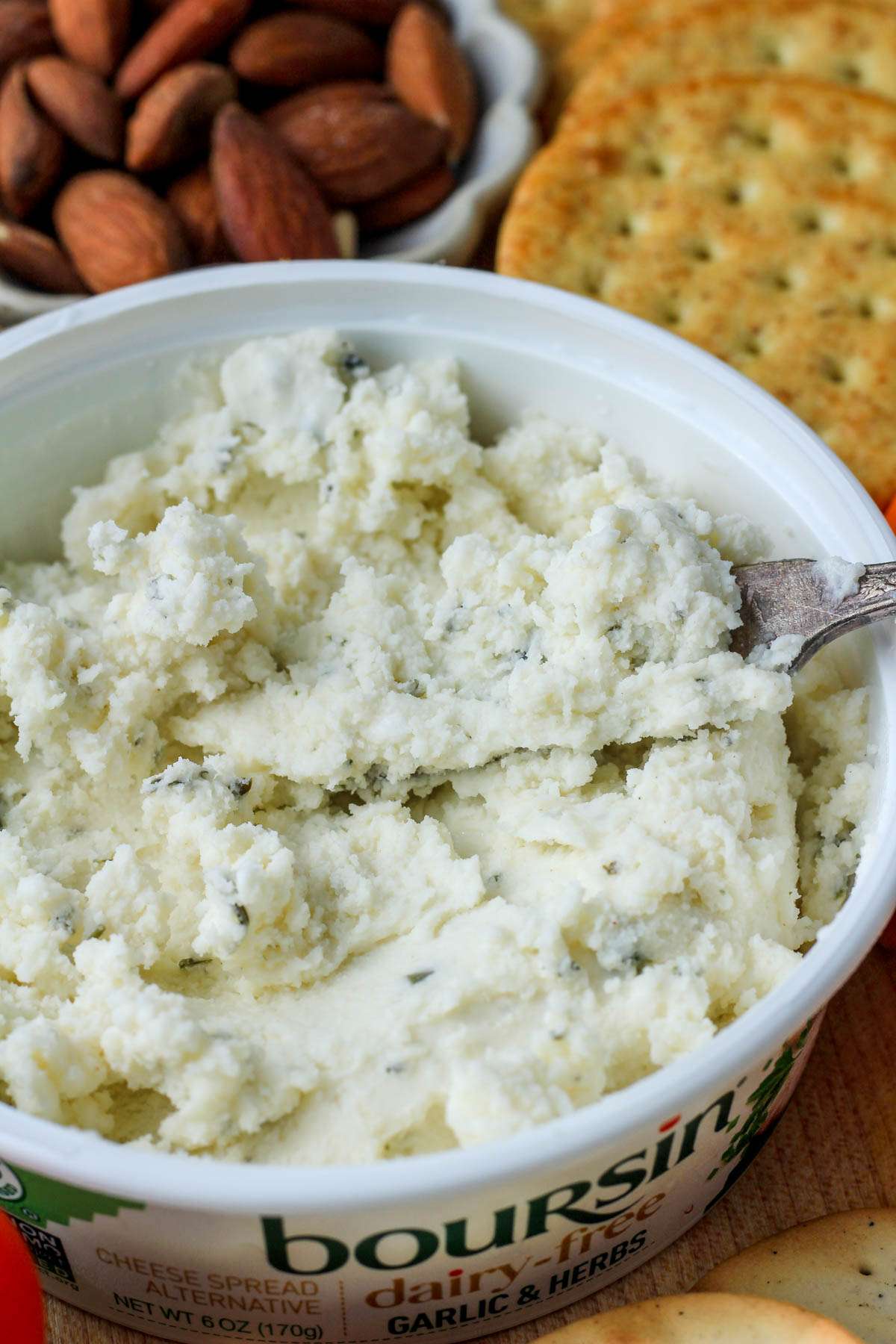 A close up picture of vegan Boursin cheese with a silver cheese spreader.