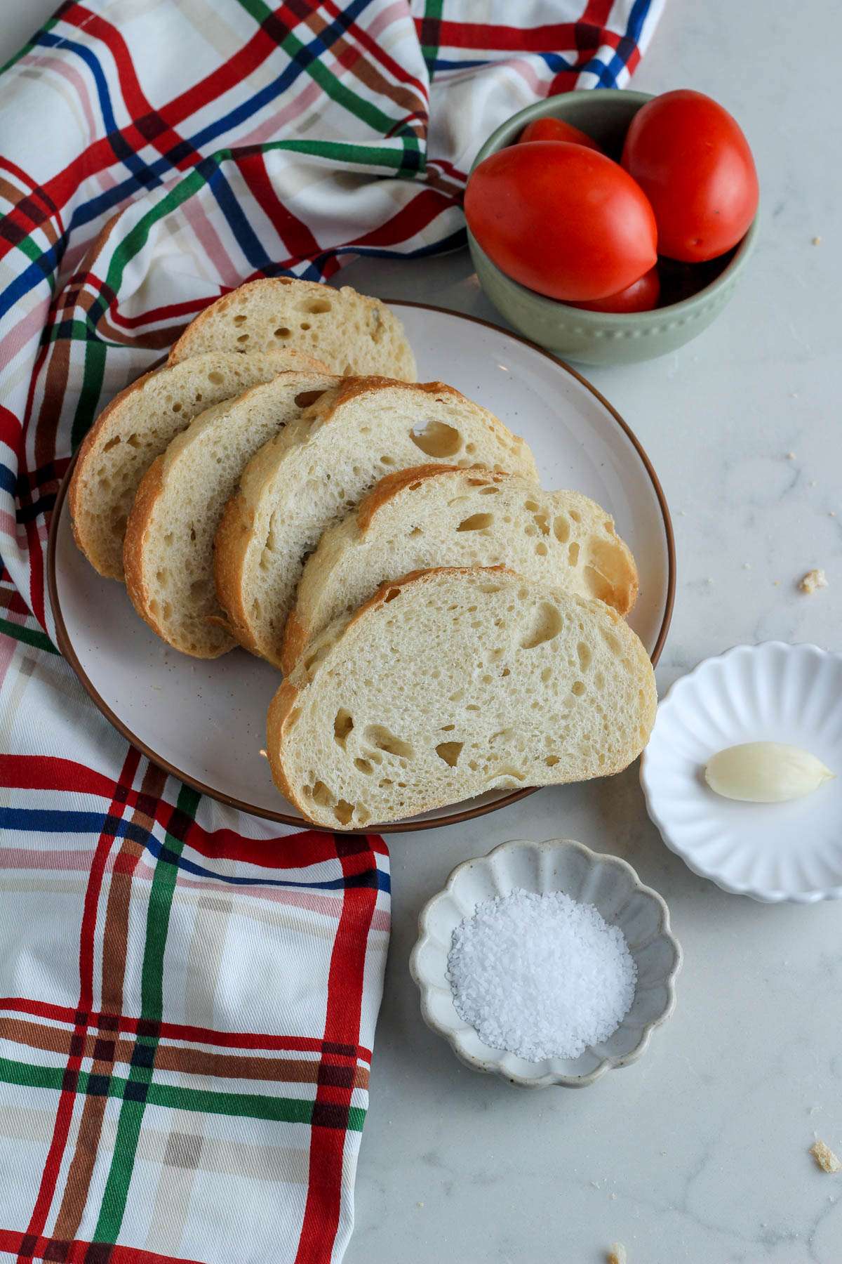 Ingredients for vegan pan con tomate on a white counter.