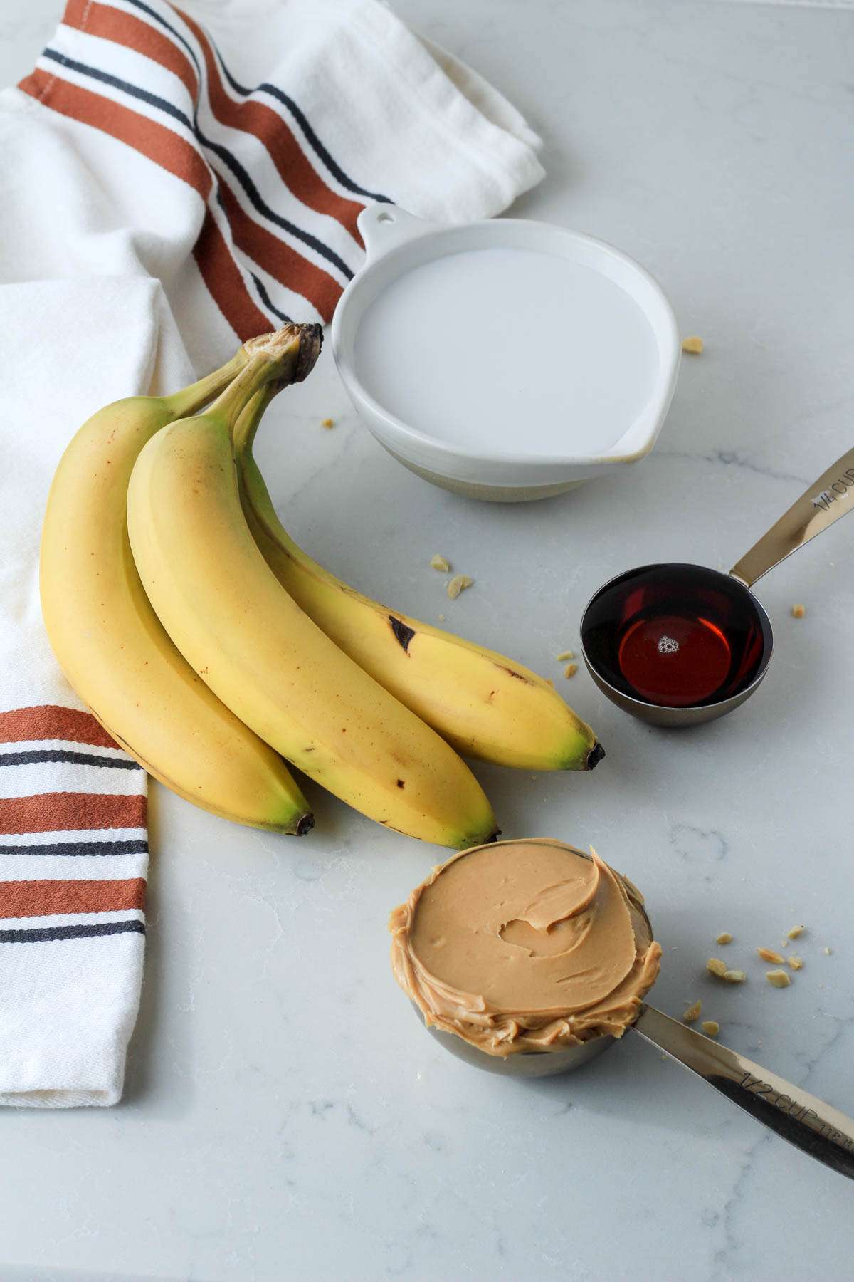 Ingredients for peanut butter banana popsicles on a white counter.