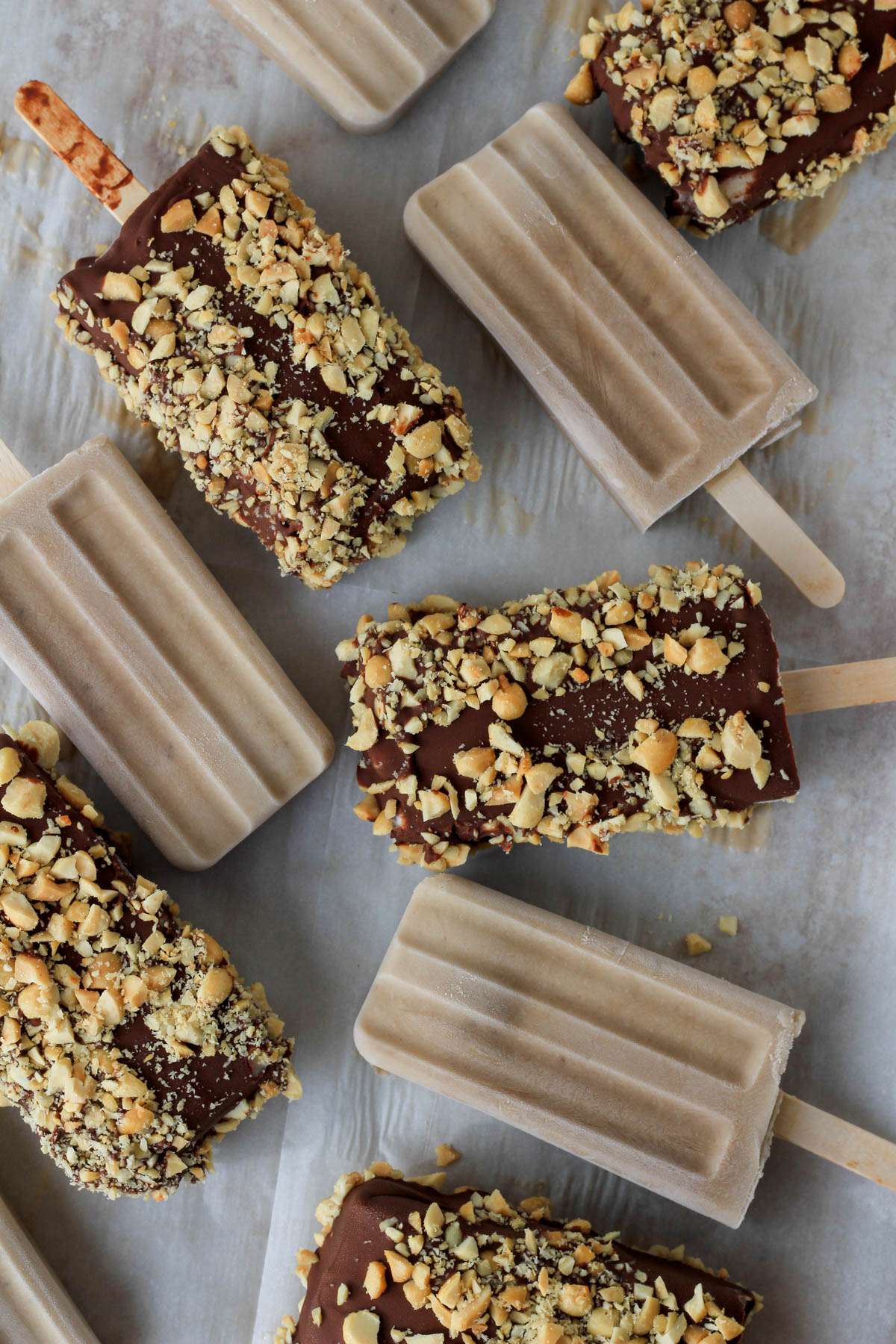 A white parchment paper covered in vegan peanut butter banana popsicles.