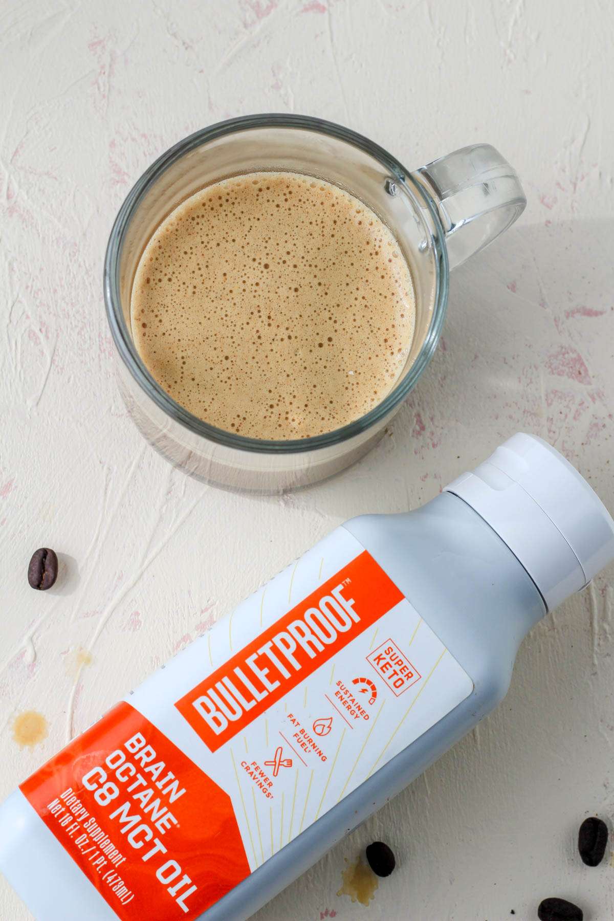 A top down picture of vegan bulletproof coffee with a bottle of MCT oil below it.