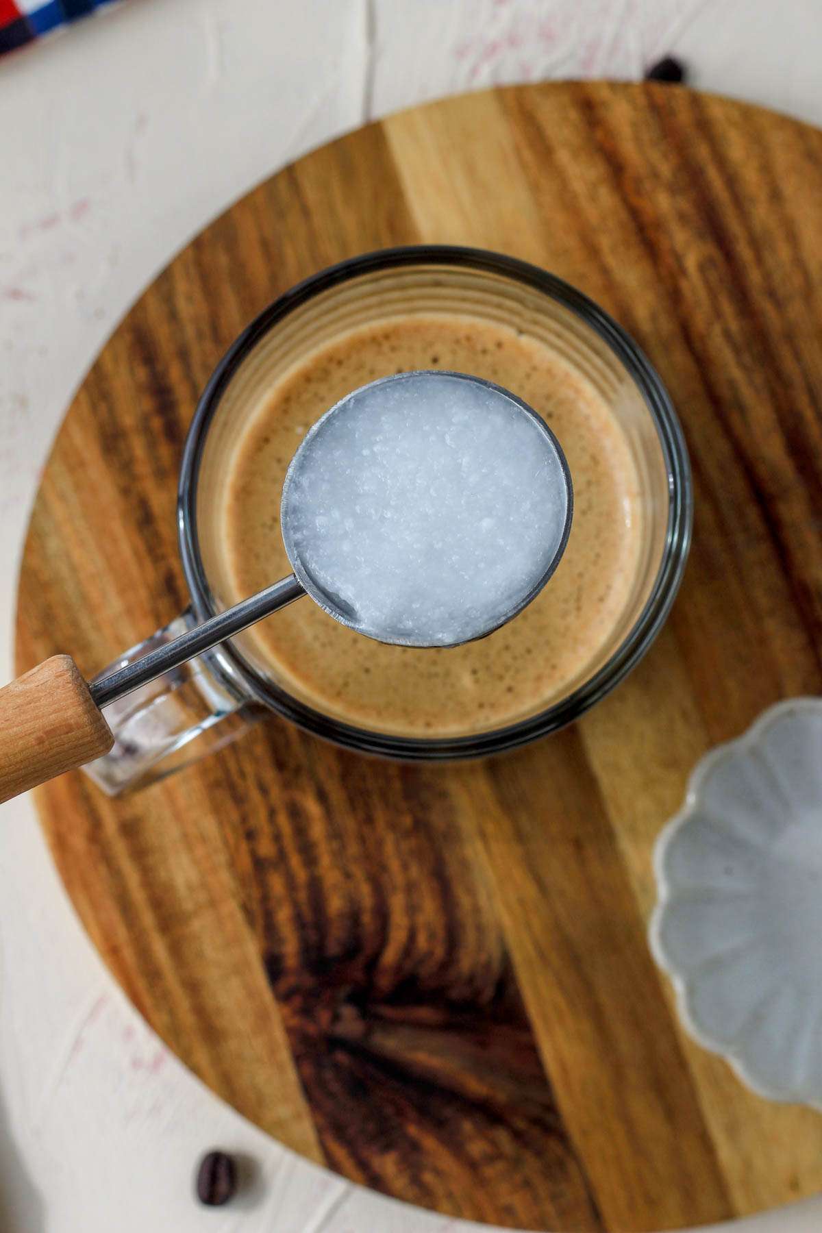 A tablespoon of coconut oil over a glass mug of vegan bulletproof coffee.