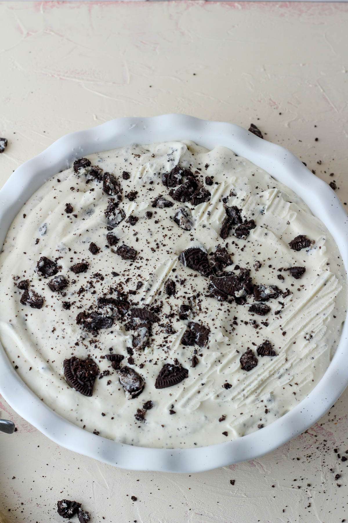 A top down picture of a white pie pan with vegan cookies and cream ice cream after freeezing.